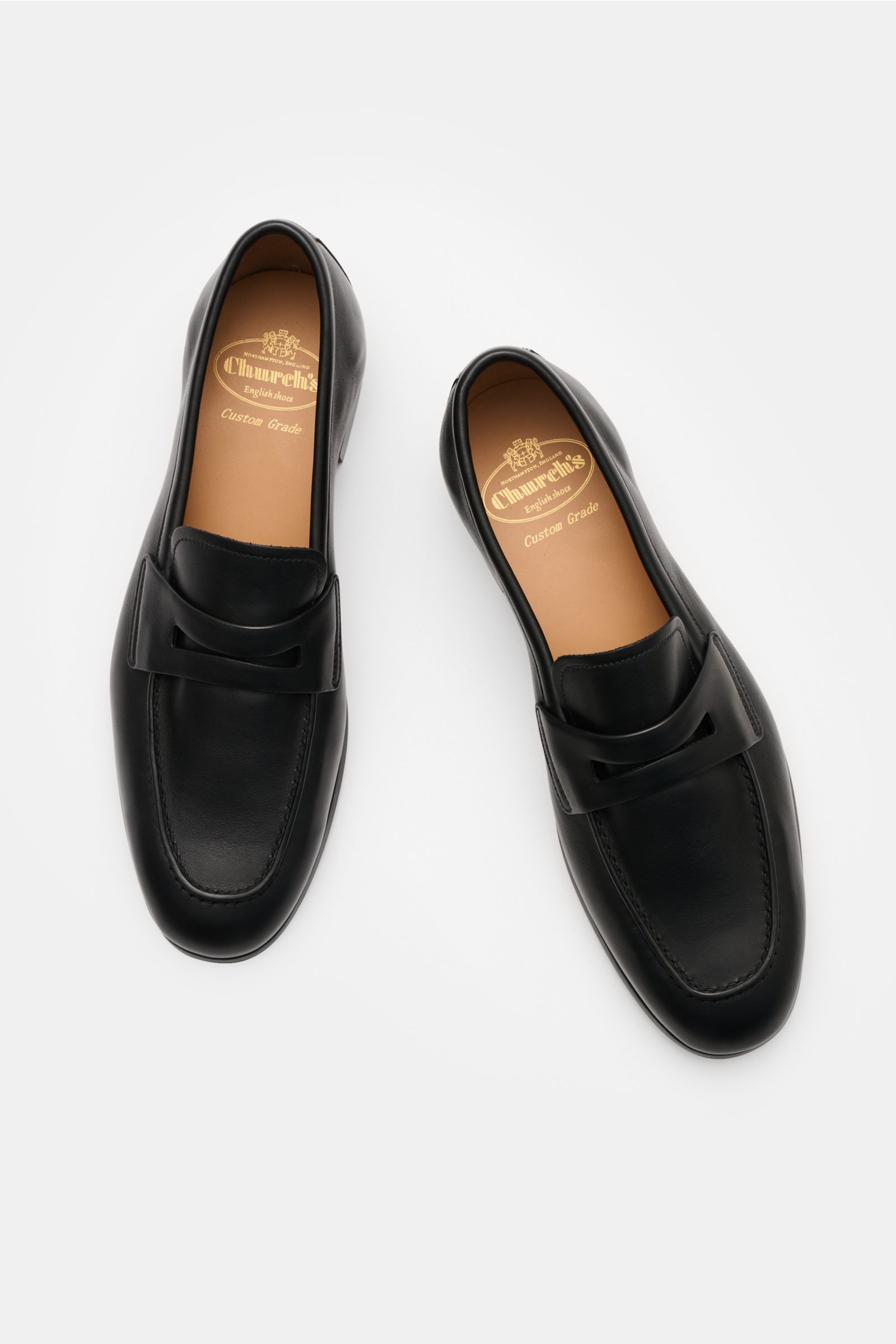 Church's Penny Loafer 'Milton' schwarz, von oben fotografiert, aus geschmeidigem Glattleder mit schmal zulaufender Silhouette, Penny-Strap, Ziernaht, ledernem Innenfutter und Kautschuksohle.