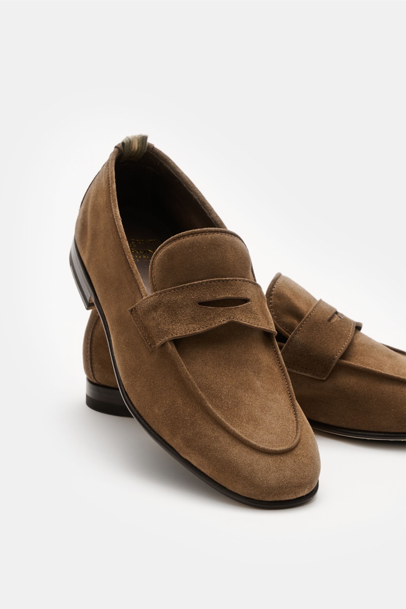 Officine Creative Penny Loafer 'Oliver' braun aus edlem Veloursleder, schmal zulaufend, mit Penny-Strap, Ziernaht, Lederfutter, Ledersohle, frontal schräg fotografiert.