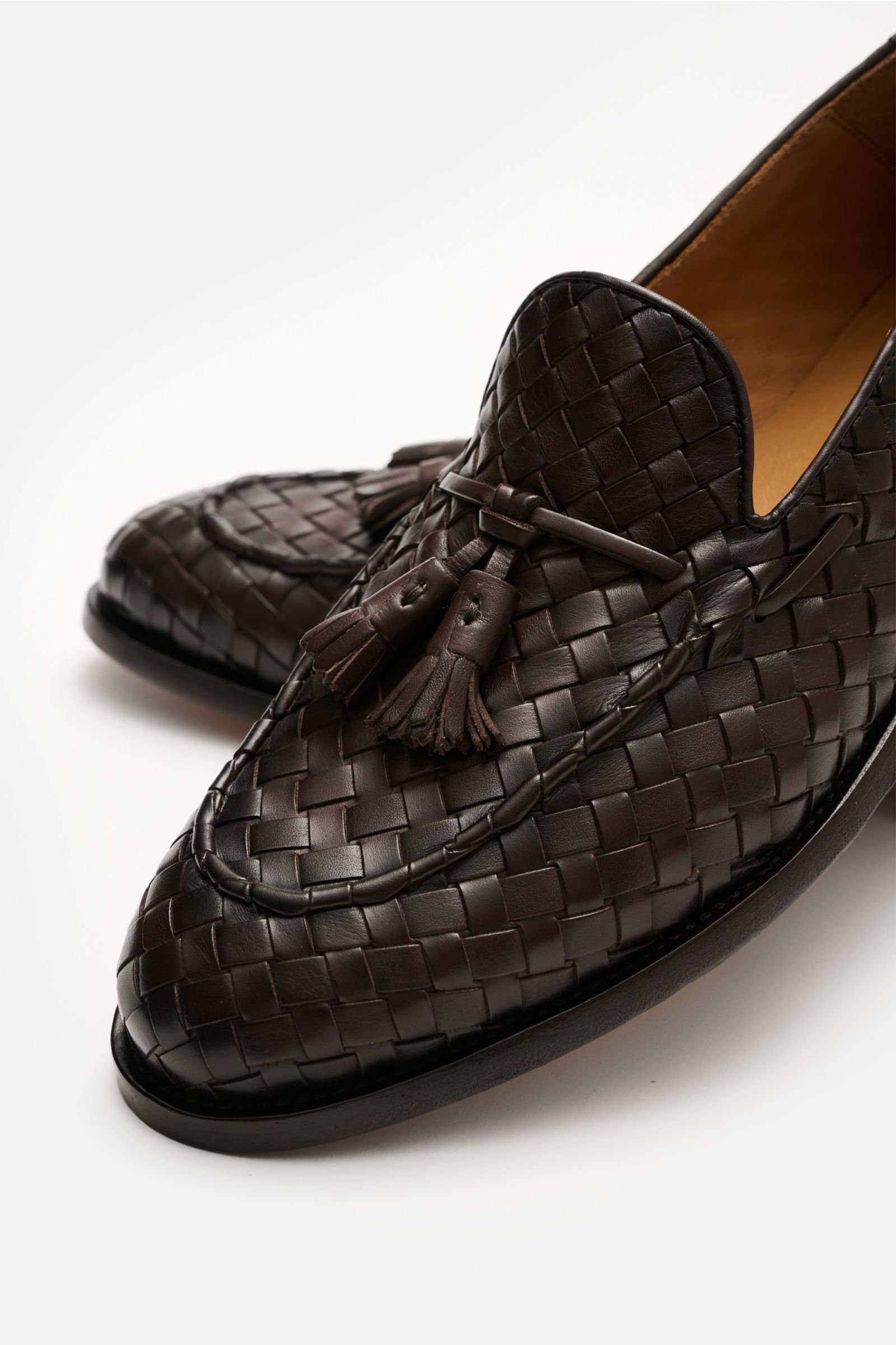 Officine Creative Tassel Loafer 'Opera' dunkelbraun aus geflochtenem Leder mit Tassels, Penny-Strap, Ziernaht, Lederfutter, Laufsohle, schmaler Silhouette, seitliche Frontperspektive.