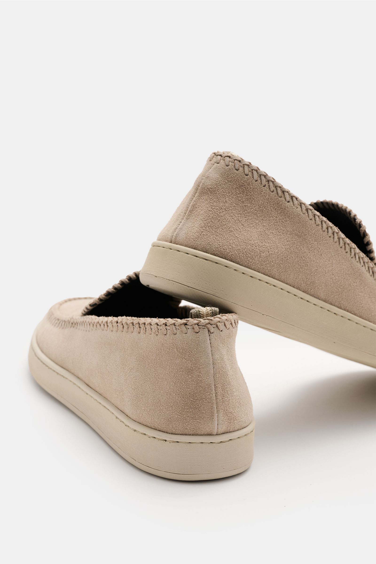 Rear angled view of Officine Creative Slipper 'Herbie' sand in soft velour leather with natural rubber sole, leather weaving, and grosgrain pull tab, showcasing its elegant, narrow silhouette.

Description: Edle Materialien wie Naturkautschuk und Veloursl