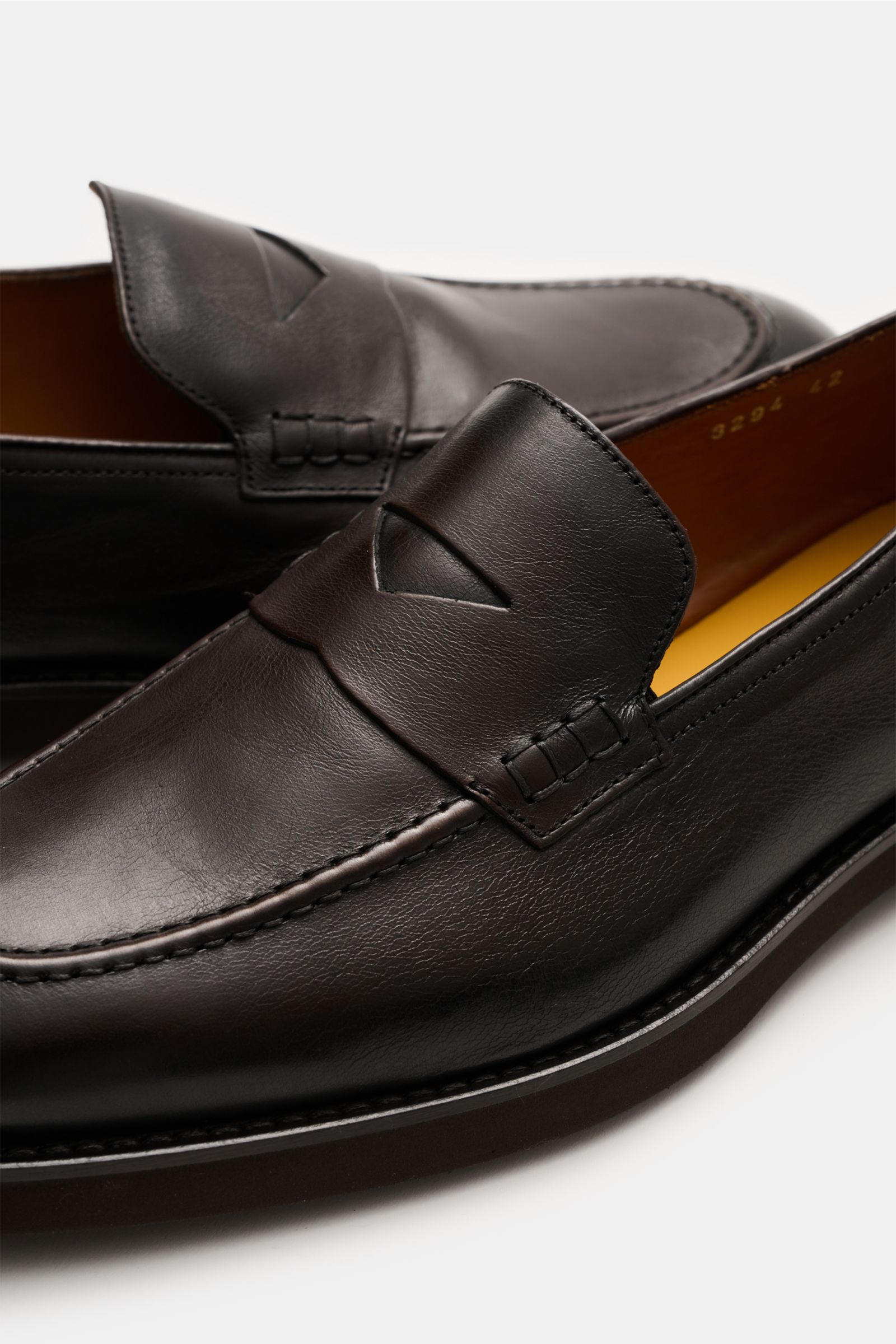 Doucal's Penny Loafer 'Triumph' dunkelbraun aus feinem Glattleder, leicht schmal zulaufend, mit Penny Strap und Steppnaht, seitliche Nahaufnahme.