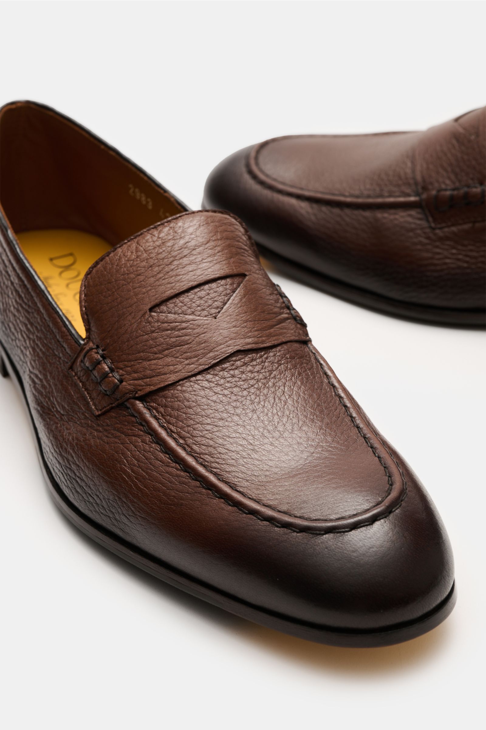 Close-up angled view of Doucal's Penny Loafer 'Daino' braun in finely grained brown leather, featuring a slim shape, penny strap, stitched toe cap, leather lining, sewn construction, and leather sole with rubber parts, perfect for trendy preppy looks.