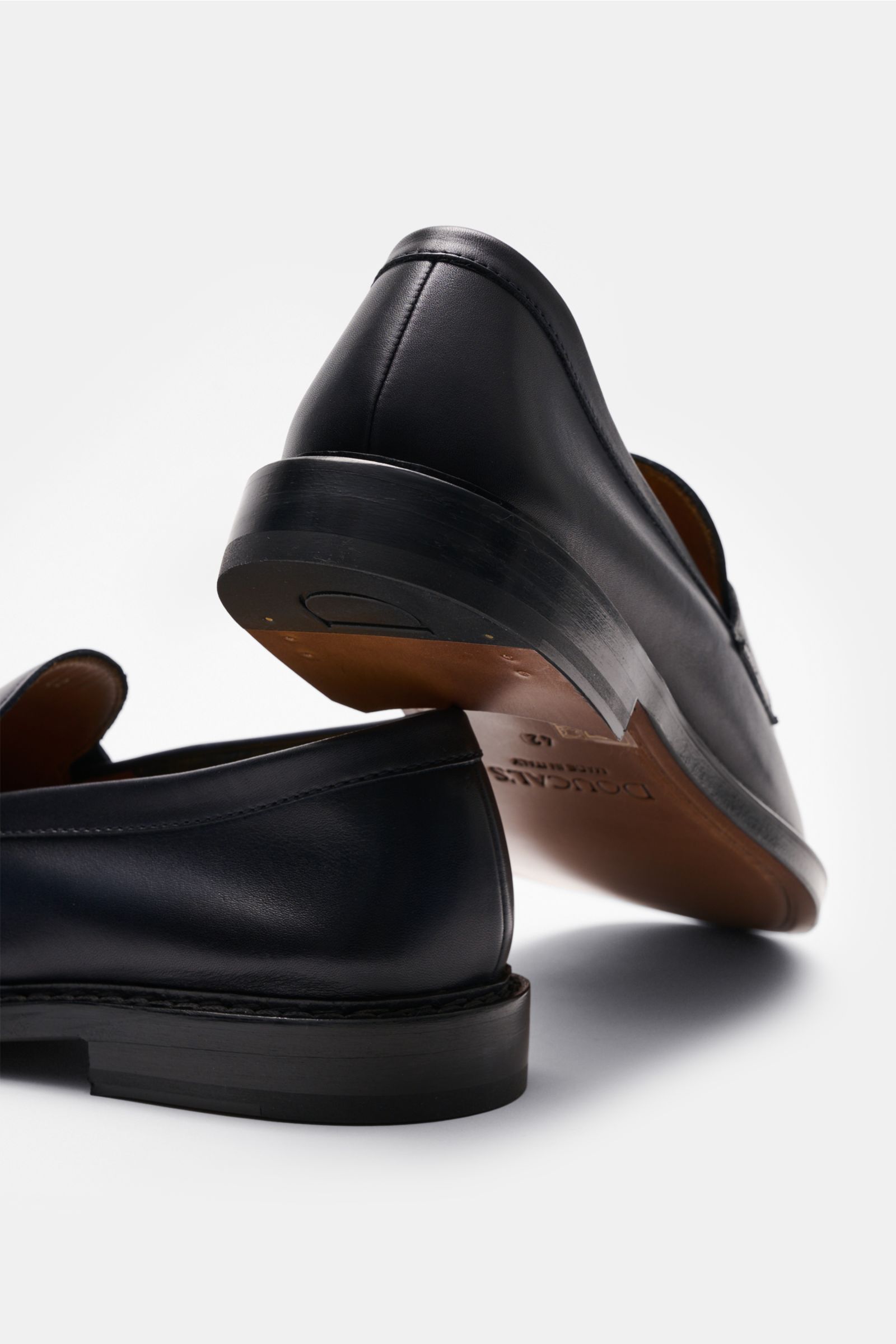Rear and side view of Doucal's Penny Loafer 'Nappato' dark navy in fine smooth leather with slight color gradient, penny strap, stitched toe cap, and leather sole, photographed from a low angle. 

Description: Wer einen klassischen Loafer sucht, liegt bei