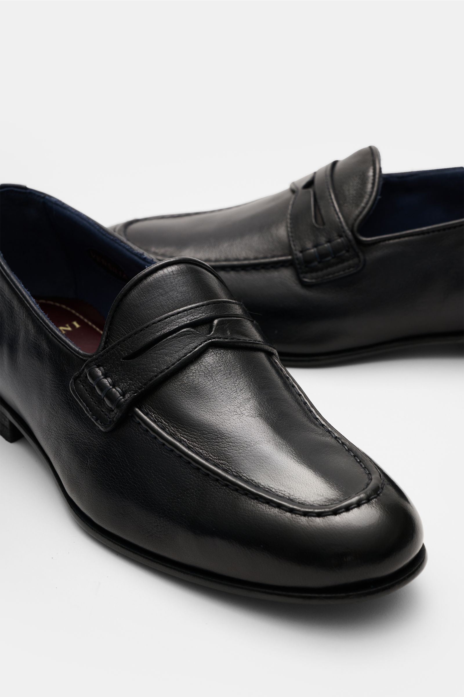 Sturlini Penny Loafer 'Bufalo' dark navy aus edlem Glattleder mit Vintage-Finish, schmal zulaufend, mit Penny Strap und Steppnaht, seitliche Nahaufnahme.