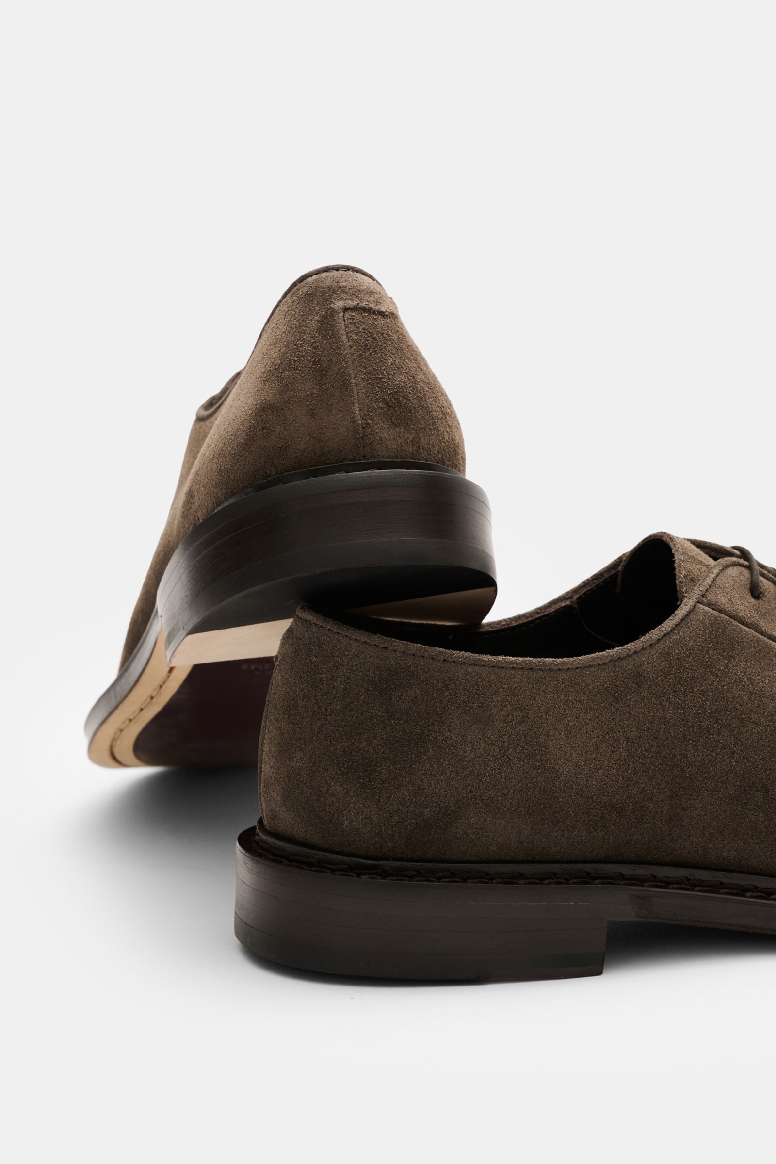 Sturlini Derby 'Softy' graubraun aus geschmeidigem Veloursleder, schmal zulaufend, offene Fünf-Loch-Schnürung, Rückansicht mit lederner Laufsohle und gekautschukverstärktem Absatz.