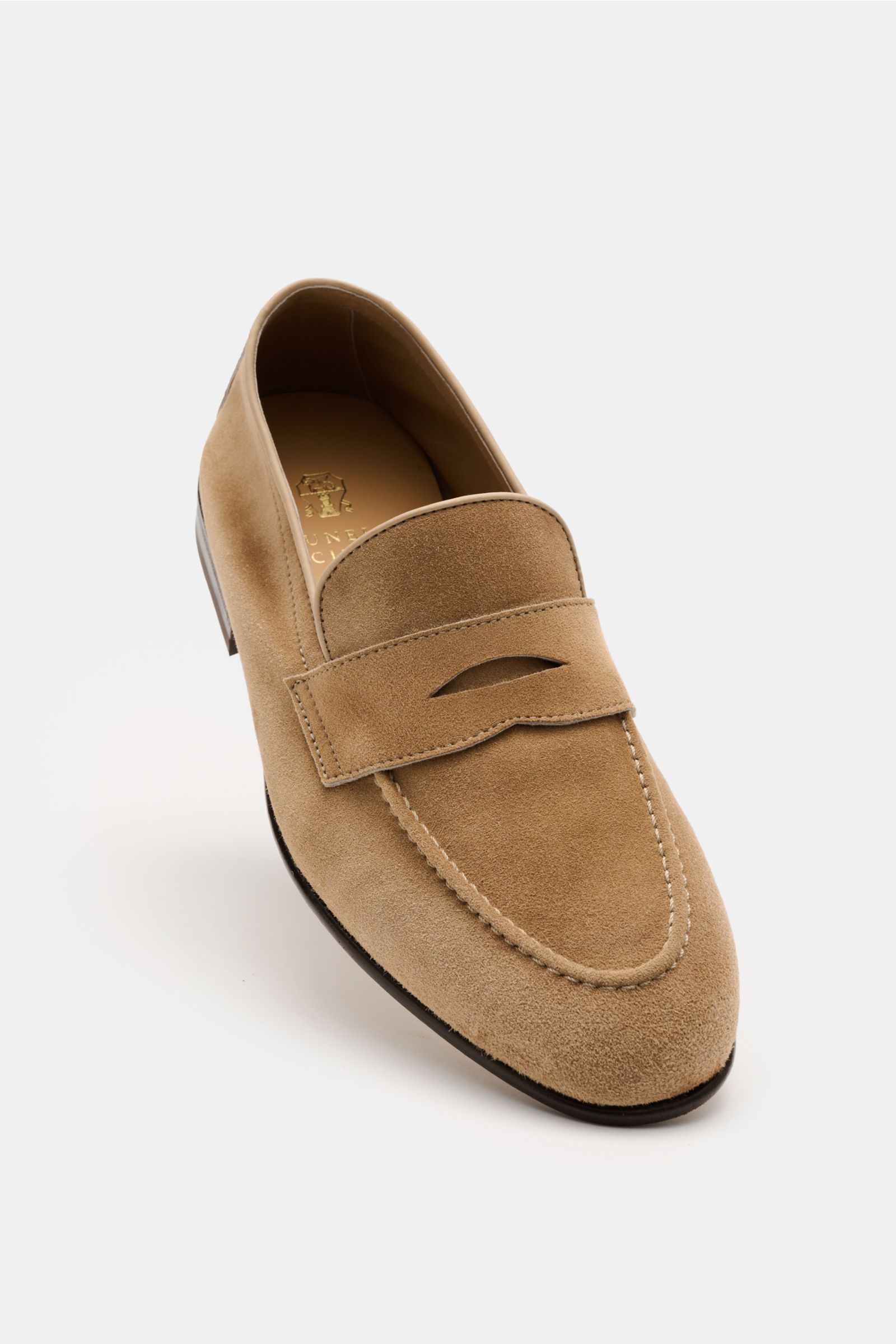 Front angled view of a beige Brunello Cucinelli Penny Loafer in soft suede velour leather, featuring a slim shape, typical penny strap, leather lining, Goodyear welted sole, and flexible leather outsole. Ein smarter Penny Loafer von BRUNELLO CUCINELLI, de