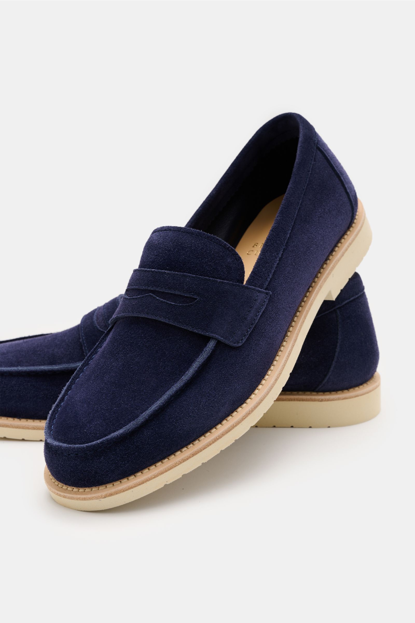 Brunello Cucinelli Penny Loafer dunkelblau aus samtigem Veloursleder, schmal zulaufend, mit Penny Strap, leichter Gummisohle, seitlich nah fotografiert.