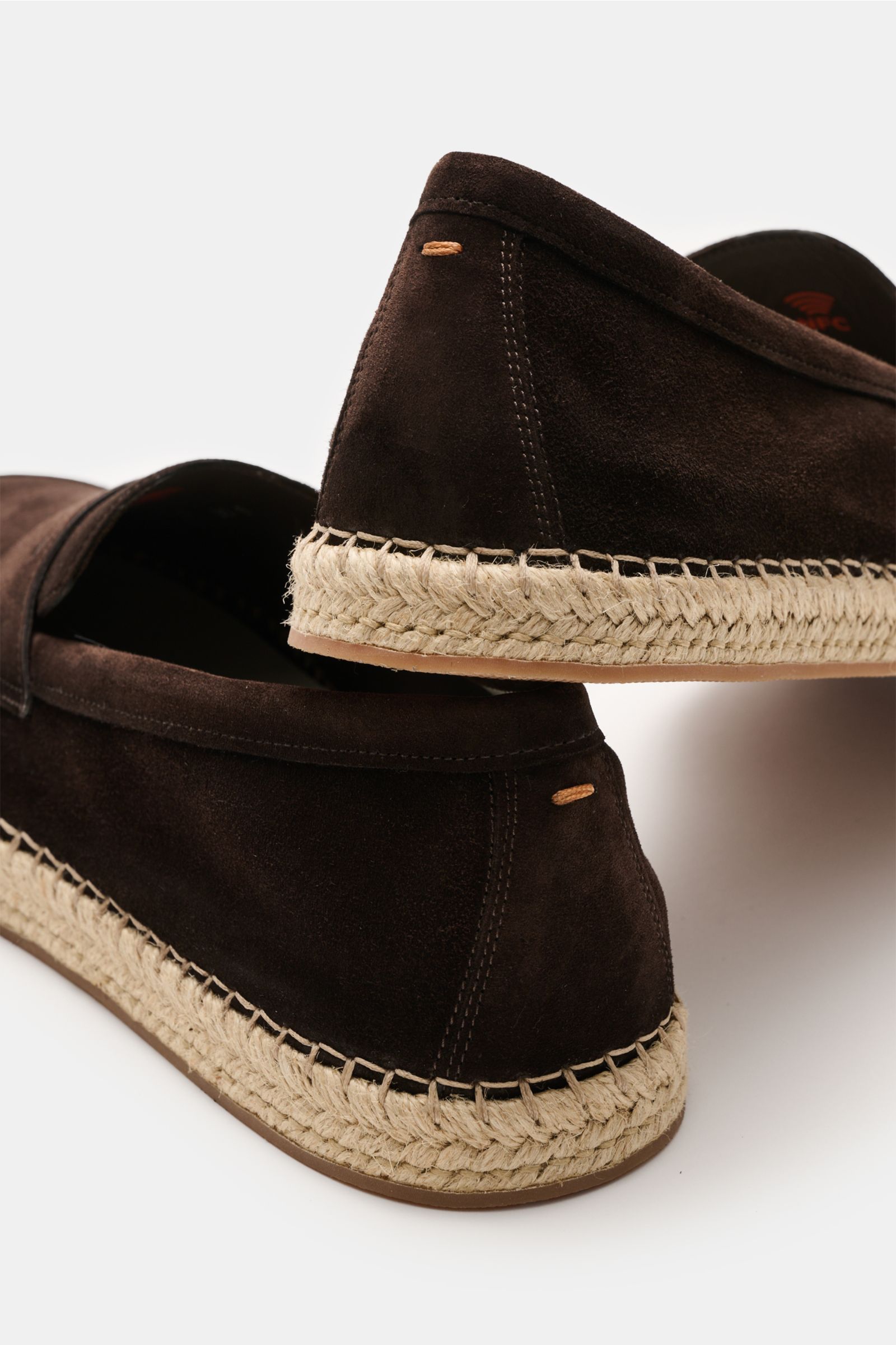 Santoni Espadrilles 'Carlo' dunkelbraun aus geschmeidigem Veloursleder mit schmal zulaufender Silhouette, Penny-Strap, Ziernaht, ledernem Innenfutter und typischer Bast-Kautschuksohle, seitlich nah fotografiert.