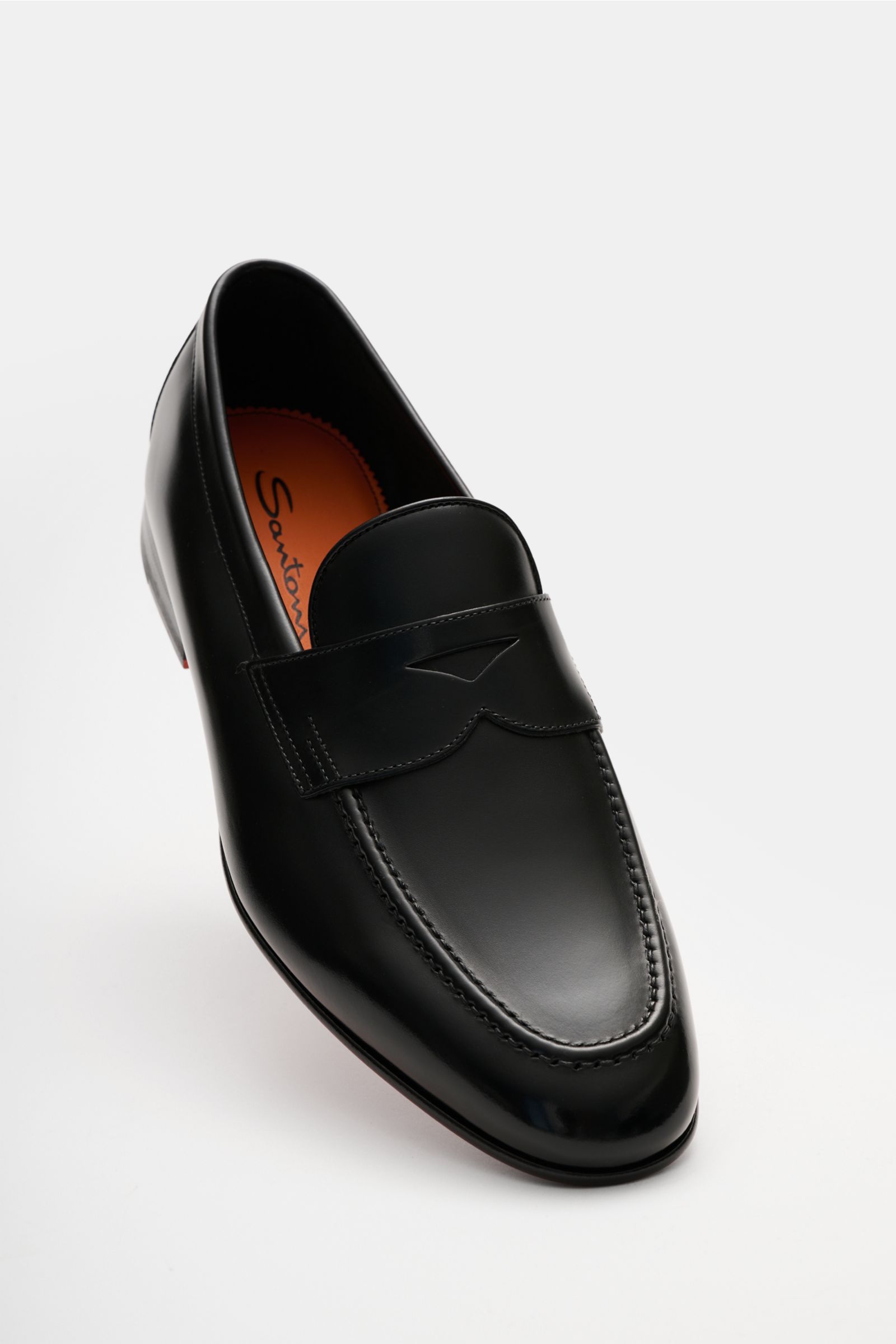 Santoni Loafer 'Carlos' schwarz aus feinem, handgefärbtem Glattleder, schmal zulaufend, mit Penny-Strap, Steppnaht, Lederfutter und orangener Sohle, frontal fotografiert.