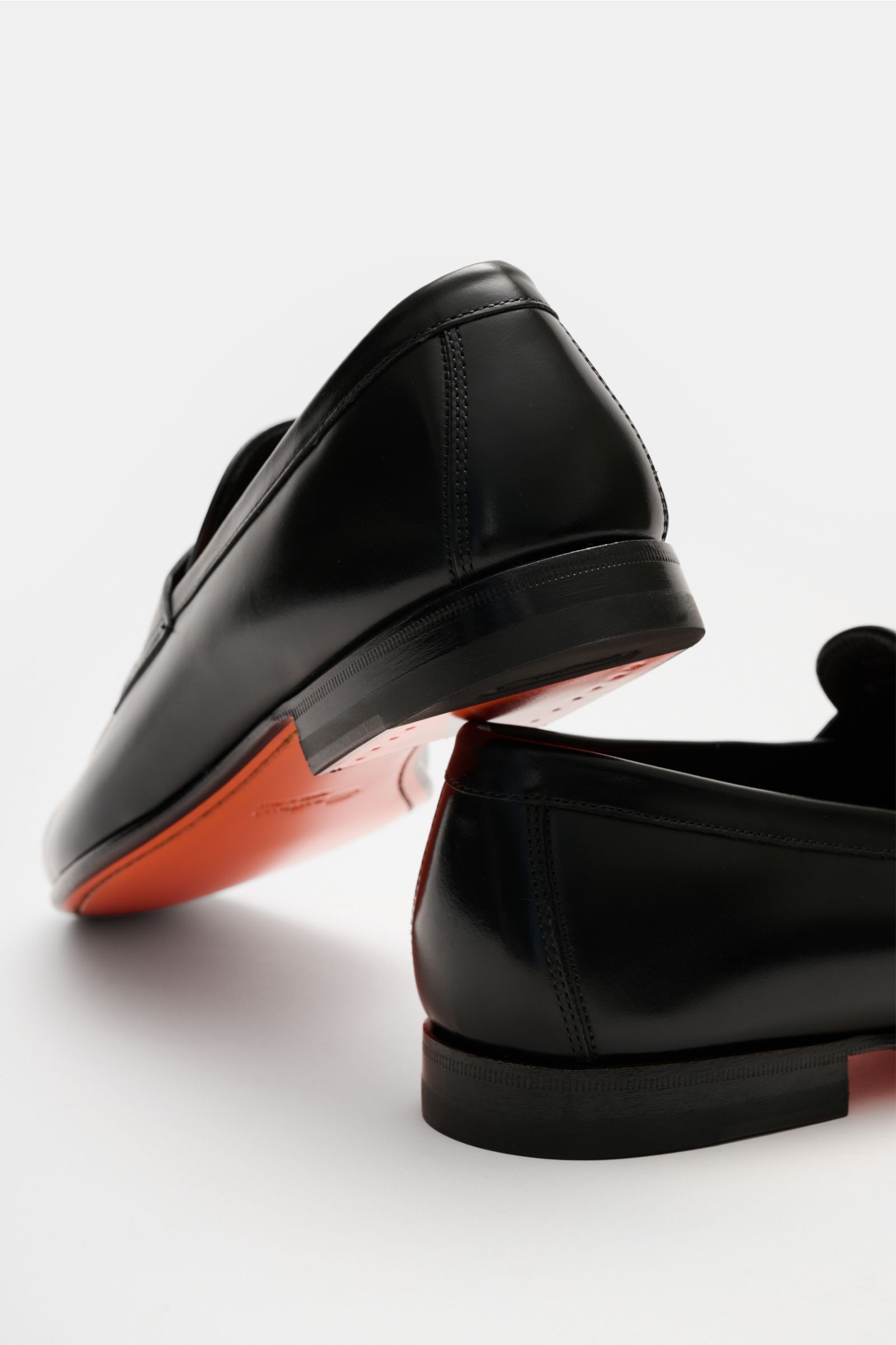 Santoni Loafer 'Carlos' schwarz aus feinem handgefärbtem Glattleder, schmal zulaufend, mit orangener Sohle, Penny-Strap, Steppnaht, Lederfutter, Lederlaufsohle, Absatz. Ansicht von hinten schräg unten.