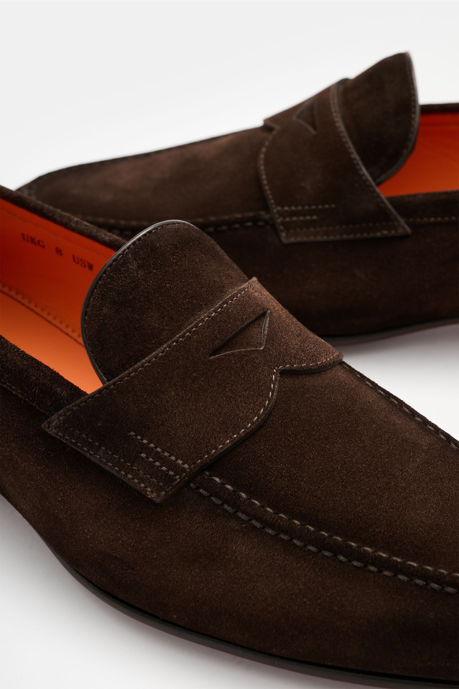 Santoni Penny Loafer 'Carlos' dunkelbraun, handgefertigt aus softem Veloursleder, schmal zulaufend, mit Penny Strap, Ziernaht, flexible Ledersohle, Nahaufnahme seitlich oben.