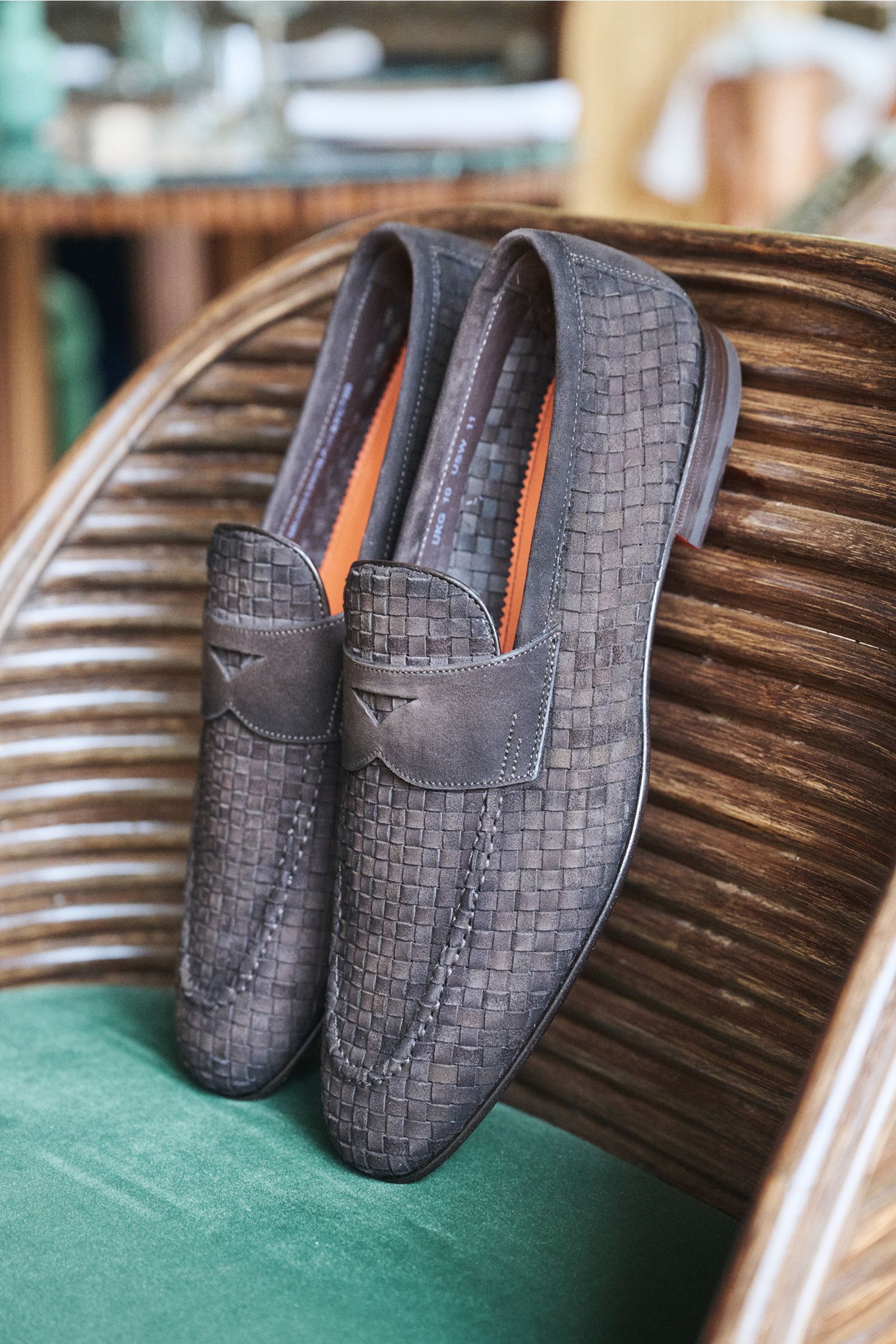 Santoni Penny loafers 'Carlo' dark brown braided suede shoes shown from a top-down angled view resting on a wooden chair with green fabric.

Perfect your sophisticated wardrobe with the penny loafers 'Carlo' by SANTONI made of braided suede with an air