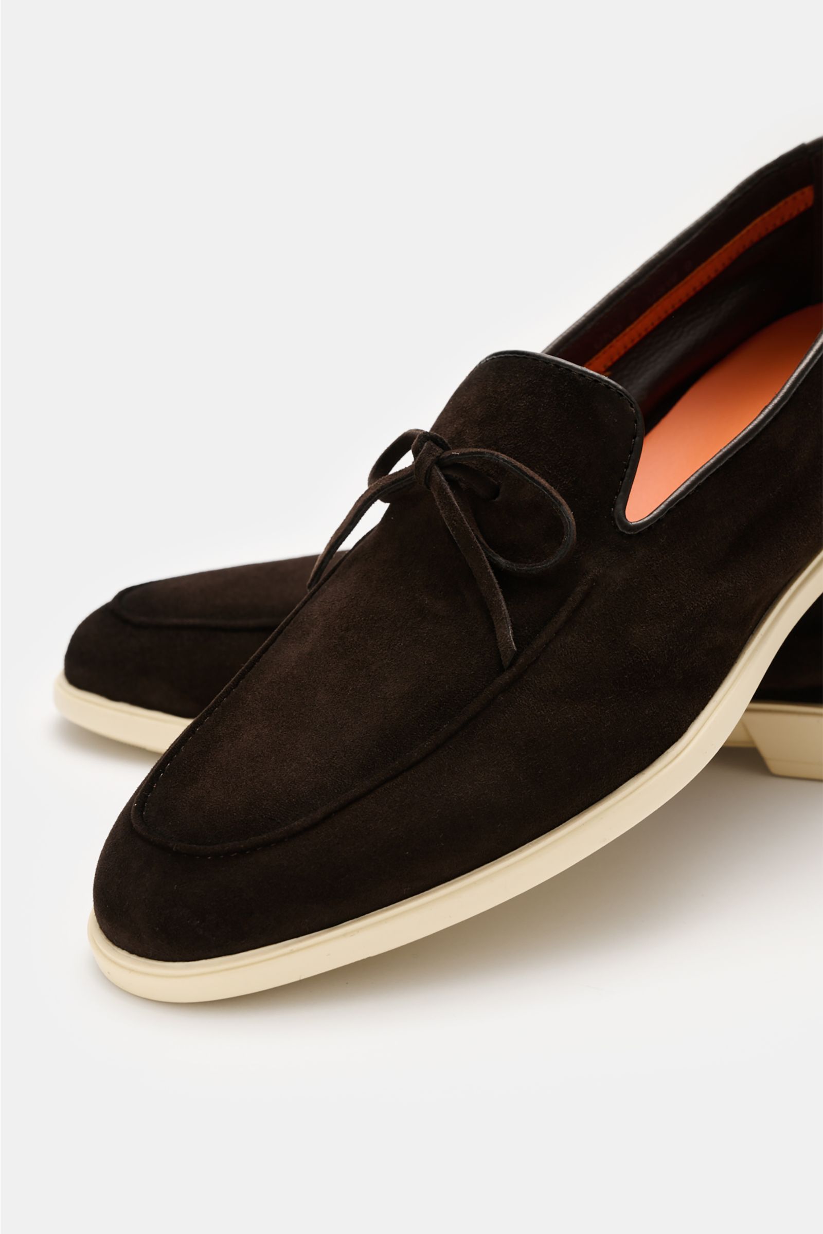 Santoni Loafer 'Malibu' dunkelbraun aus geschmeidigem Veloursleder, schmal zulaufend, mit Zierschleife, heller Kautschuksohle, seitliche Perspektive.