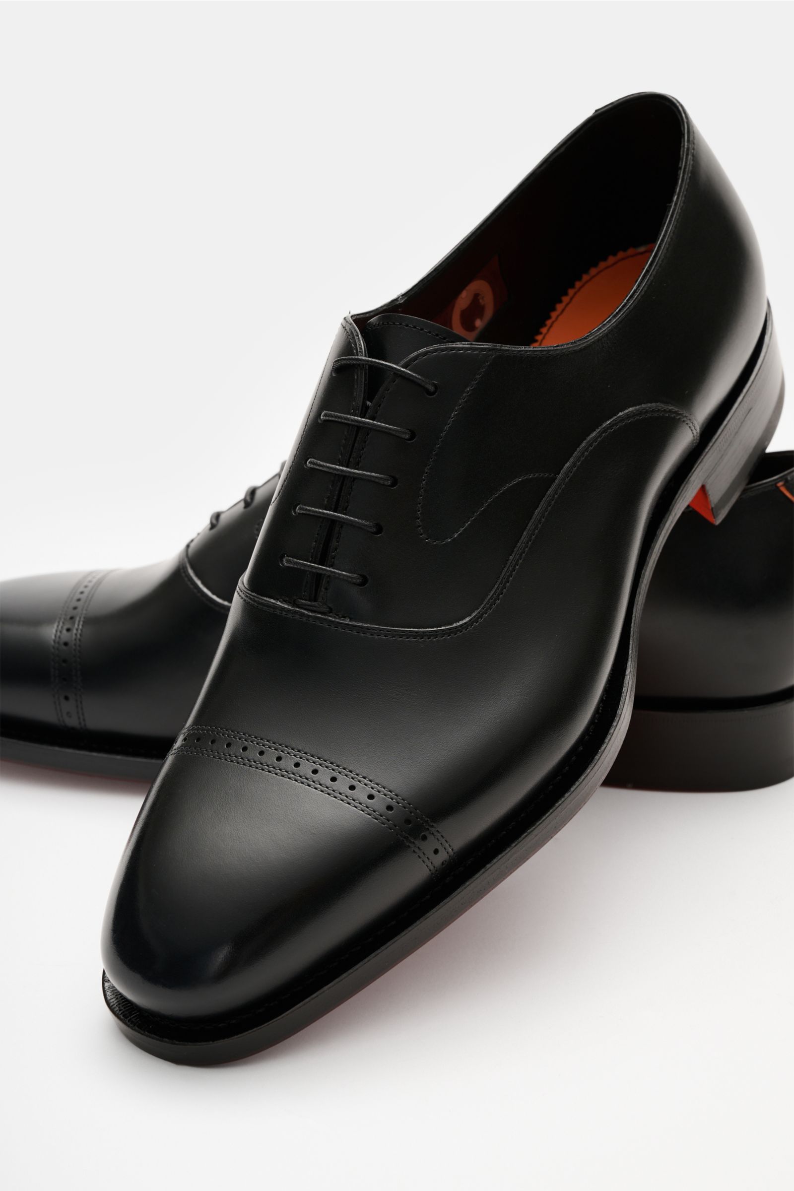 Santoni Oxford 'Adrian' schwarz, elegant aus hochwertigem Glattleder, schmal zulaufend, Goodyear-welted, mit geschlossener Fünf-Loch-Schnürung, Querkappe, Lederinnenfutter, Ledersohle und kautschukverstärktem Absatz, seitlich von oben fotografiert.
