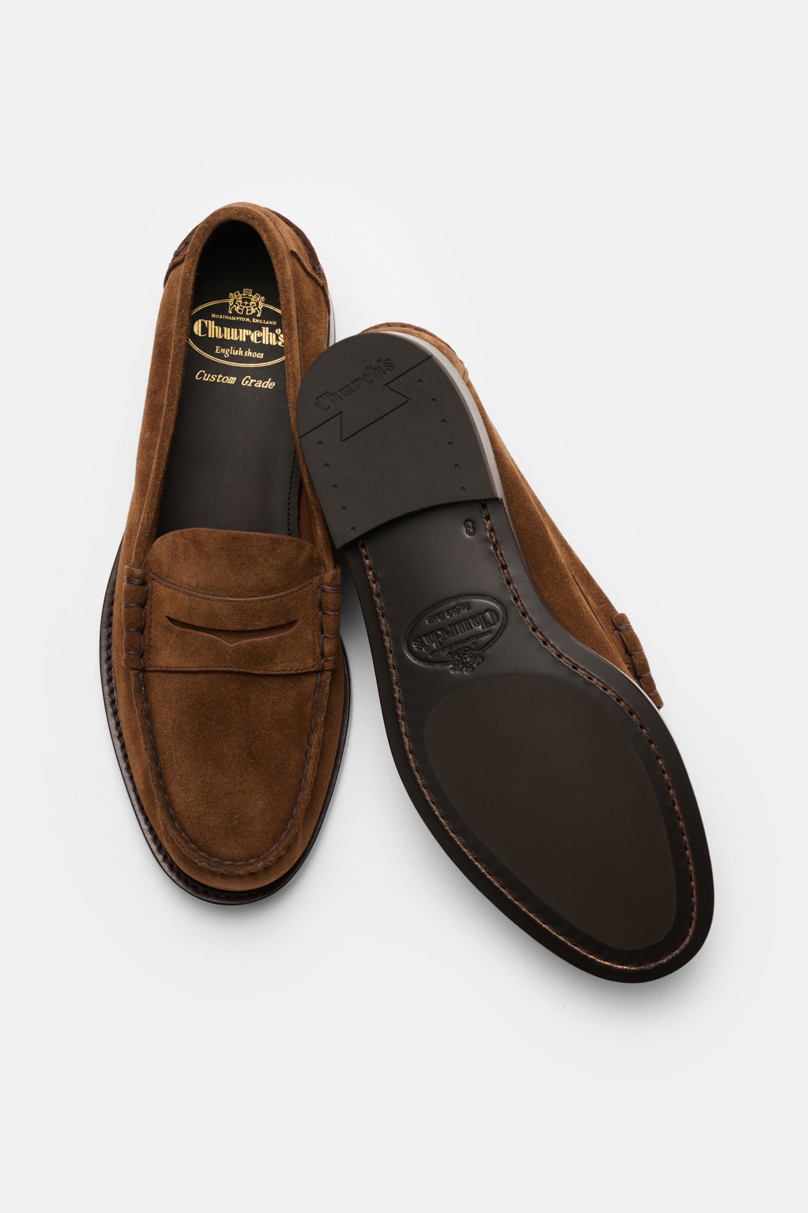 Top and sole view of Church's Penny Loafer 'Rowley' braun in brown suede with penny strap, decorative stitching, and leather sole.

Description: Der Penny Loafer 'Rowley' von CHURCH'S besticht durch seine Ziernähte und das geschmeidige Veloursleder – p