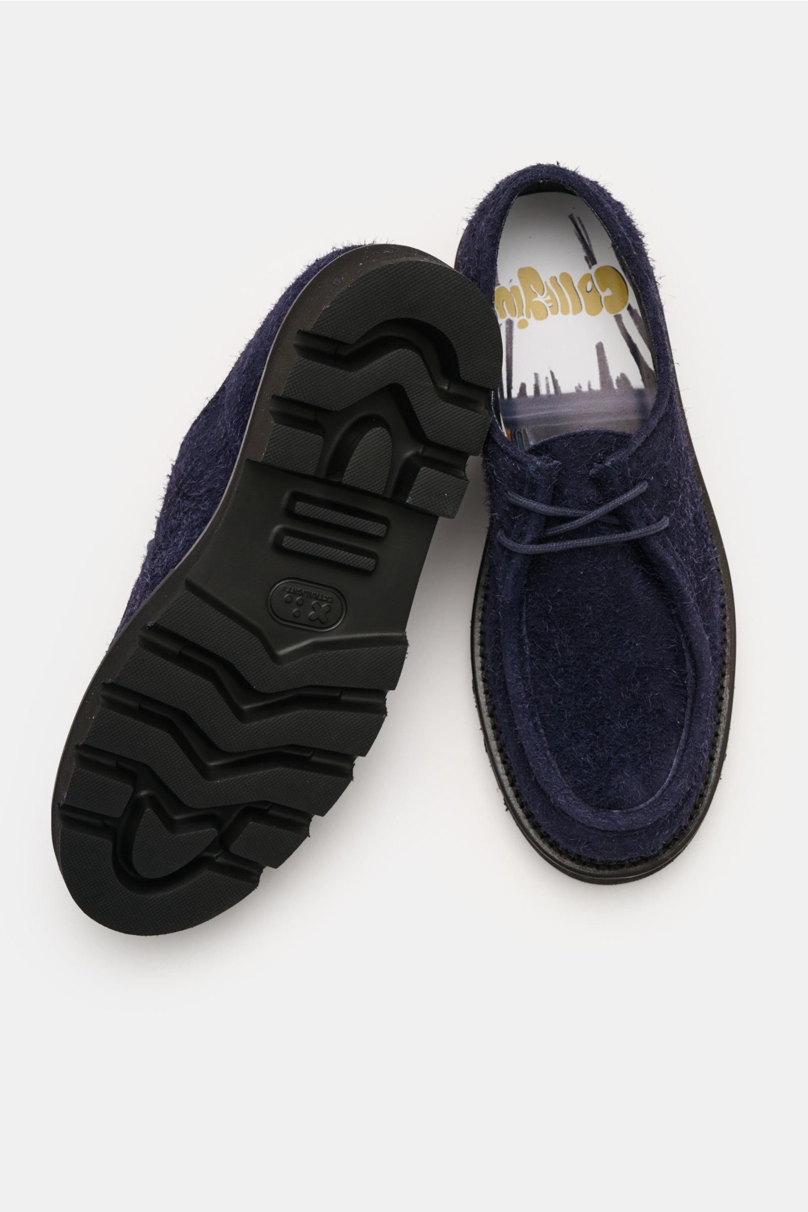 Collegium Derby 'Pillar Moc-Toe' navy shoes shown from top and sole views, with smooth navy velour leather, slim silhouette, open two-eyelet lacing, decorative cap stitching, leather lining, and profiled rubber outsole. Eyecatcher for transitional seasons