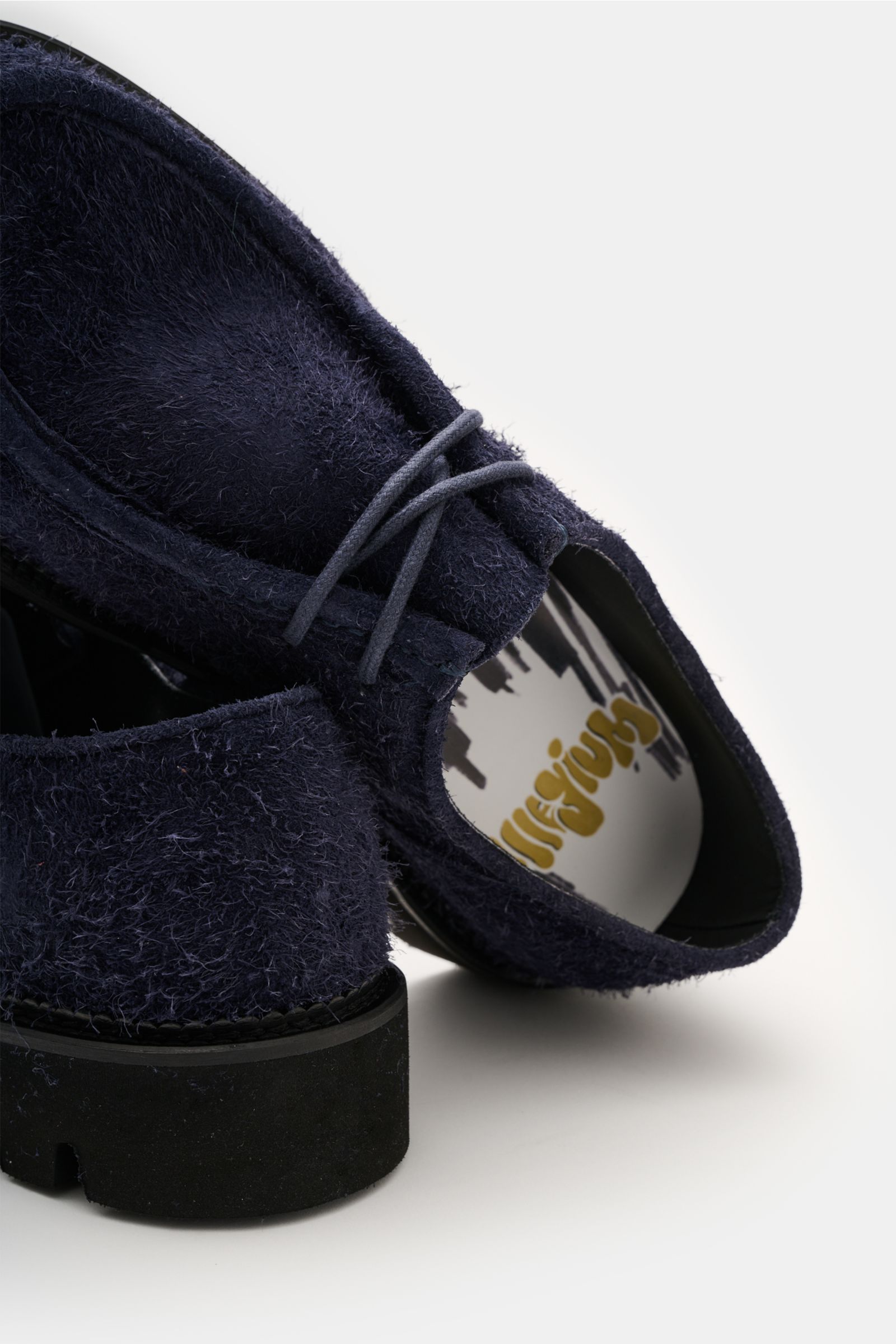 Close-up rear and top view of the Collegium Derby 'Pillar Moc-Toe' navy shoe, showcasing its smooth velour leather, slim silhouette, open two-eyelet lacing, decorative toe cap stitch, leather lining, and rubber profile sole. Eyecatcher for transitional se