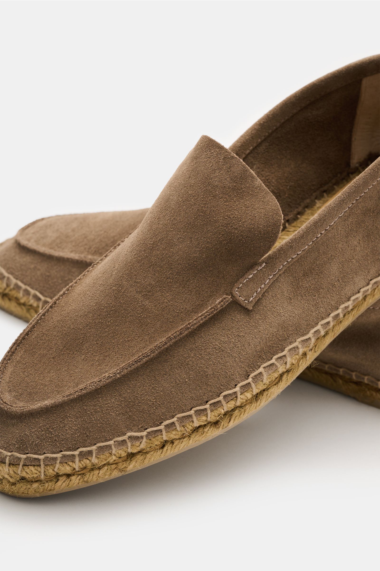 Close-up angled view of Castañer Espadrilles 'Nino T' taupe in supple suede with a slightly tapered cut, decorative toe seam, practical pull loop, braided jute edging, and flexible natural rubber sole, showcasing summery lightness and Mediterranean style 
