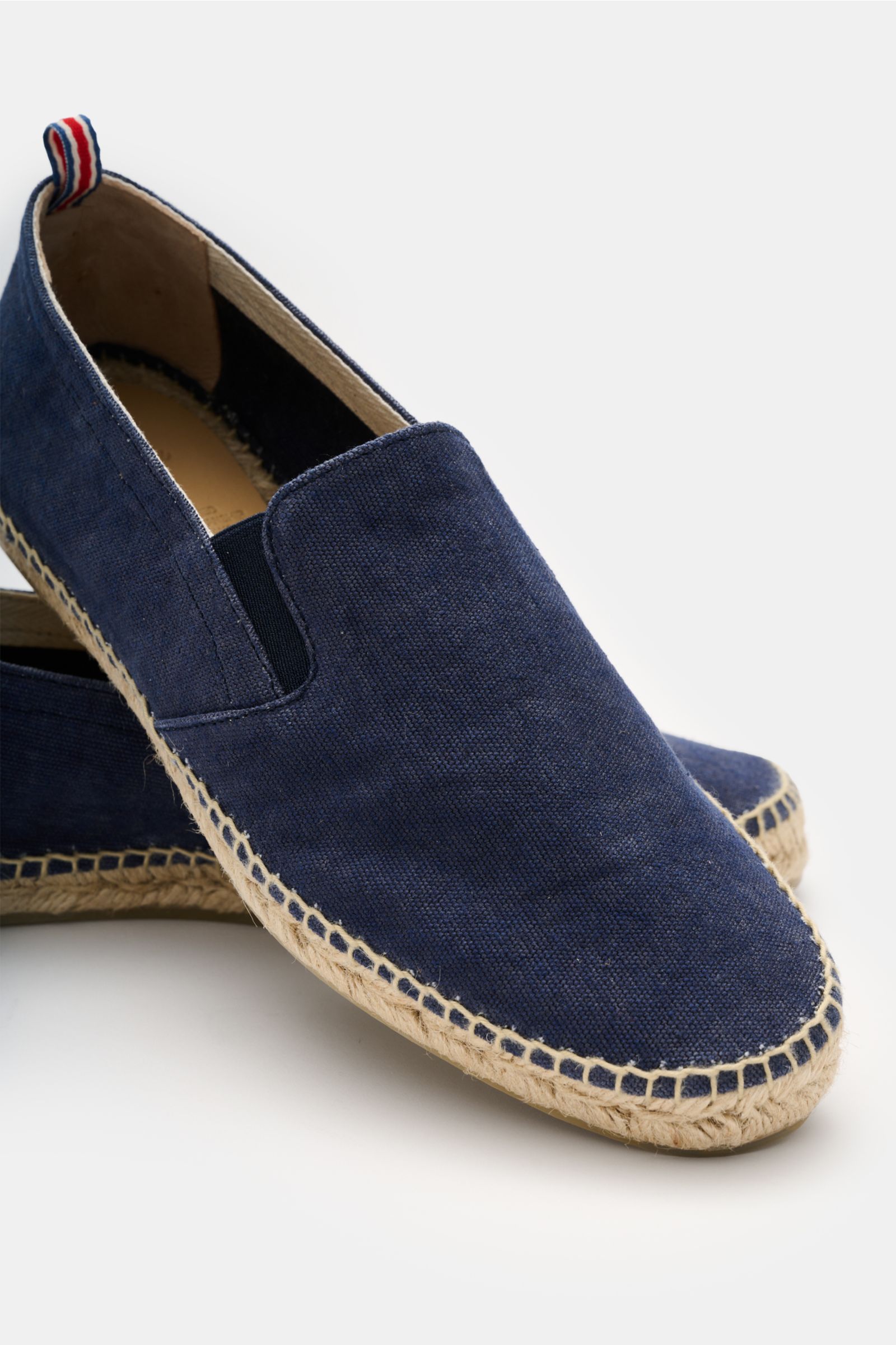 Castañer Espadrilles 'Joel' navy shown from a front-side angle, featuring navy cotton canvas, elastic inserts, decorative back stitching, jute trim, and flexible rubber sole. Die Espadrilles 'Joel' von CASTAÑER aus Canvas verbinden gekonnt die markenty