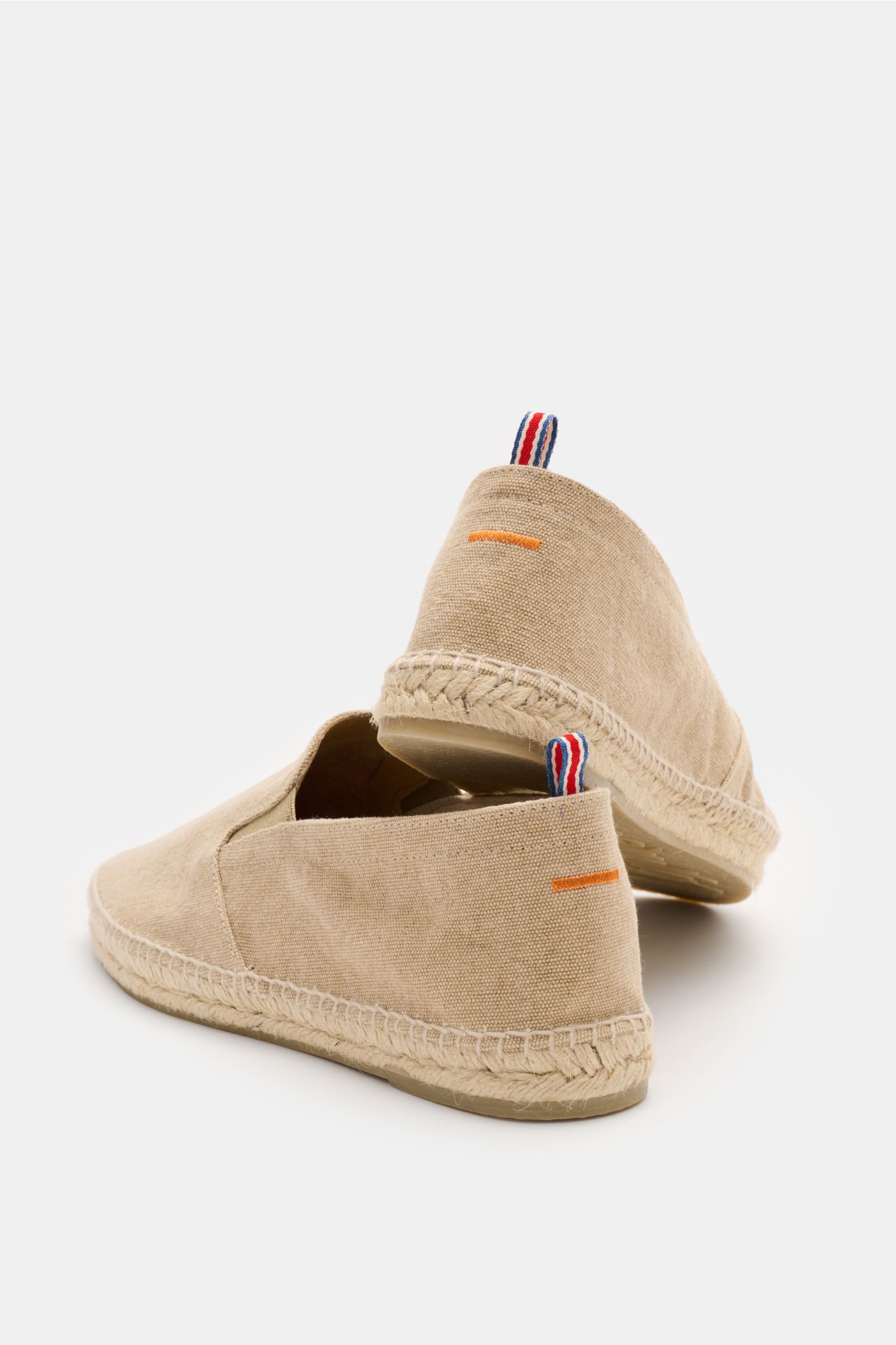 Rear-side view of Castañer Espadrilles 'Joel' beige in cotton canvas with jute trim and flexible rubber sole, elastic inserts, decorative back stitch, and pull loop.

Die Espadrilles 'Joel' von CASTAÑER aus Canvas verbinden gekonnt die markentypische v
