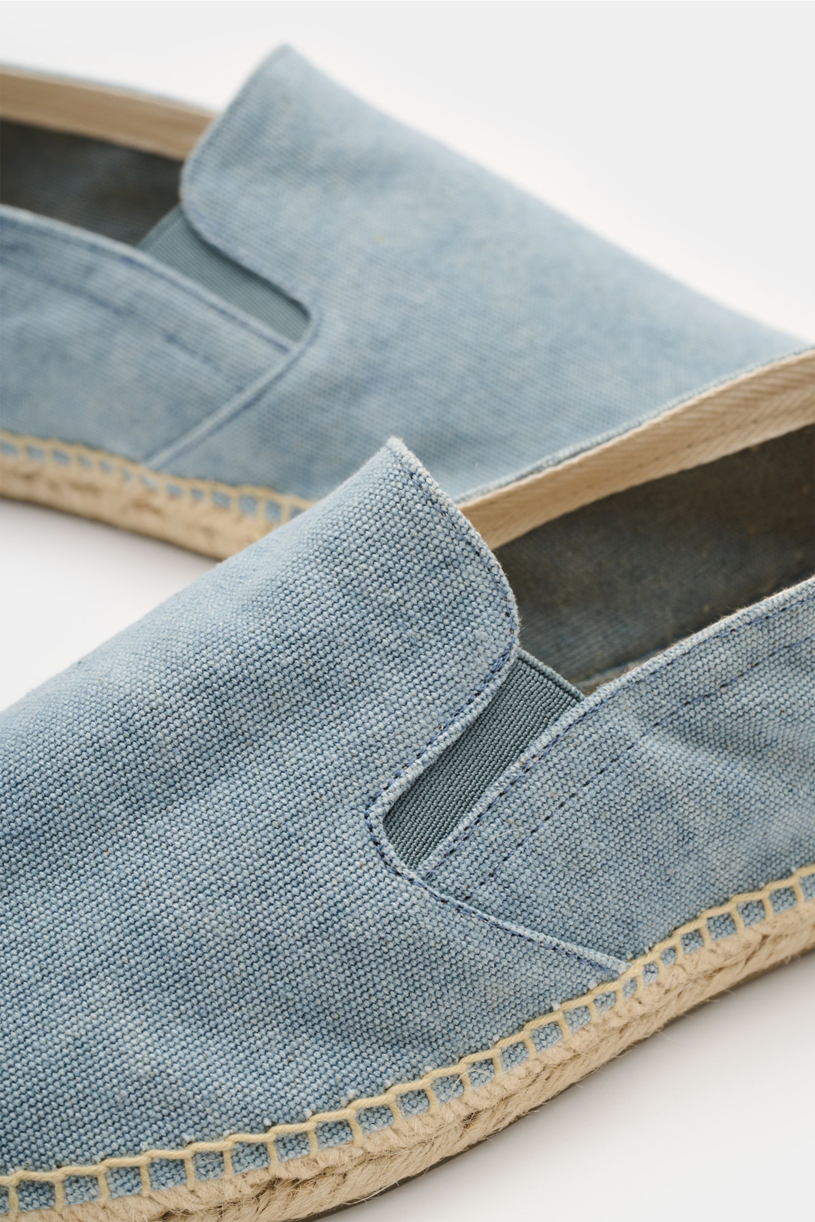 Close-up side view of Castañer Espadrilles 'Joel' rauchblau in blue canvas with elastic inserts, jute edging, decorative back stitching, pull loop, and flexible rubber sole. Die Espadrilles 'Joel' von CASTAÑER aus Canvas verbinden gekonnt die markentypisc