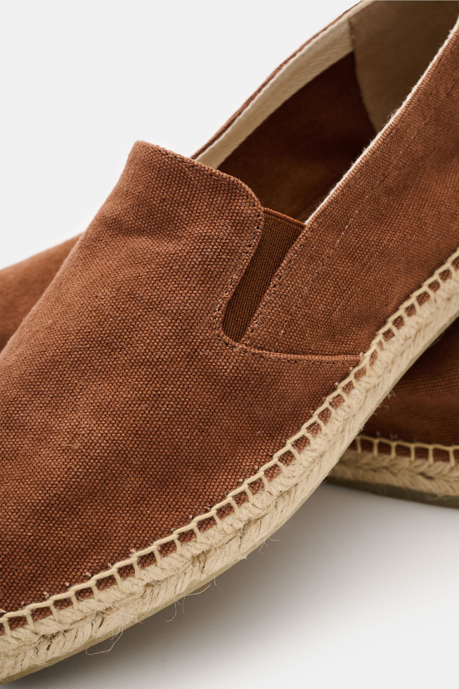 Castañer Espadrilles 'Joel' rostbraun in close-up from a side angle, showing cotton canvas upper, elastic inserts, decorative stitching, jute trim, and flexible rubber sole. Die Espadrilles 'Joel' von CASTAÑER aus Canvas verbinden gekonnt die markentyp