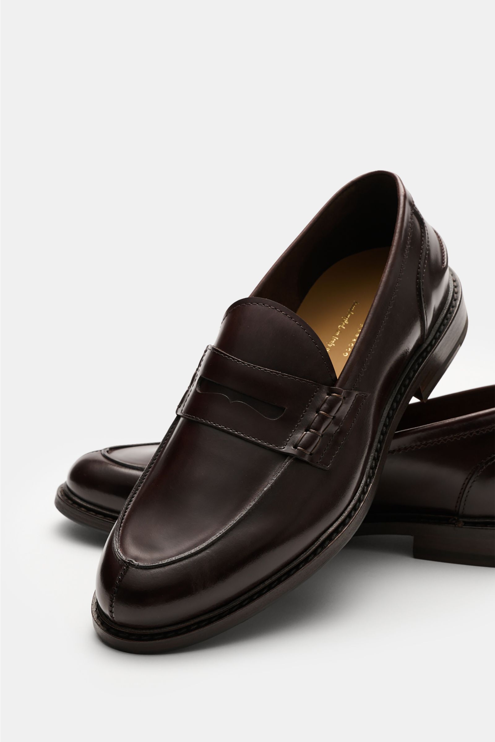 Henderson Penny Loafer 'Calf Lux Sparrow' dunkelbraun aus poliertem Glattleder, schmal, mit Penny-Strap, seitlich von oben fotografiert.