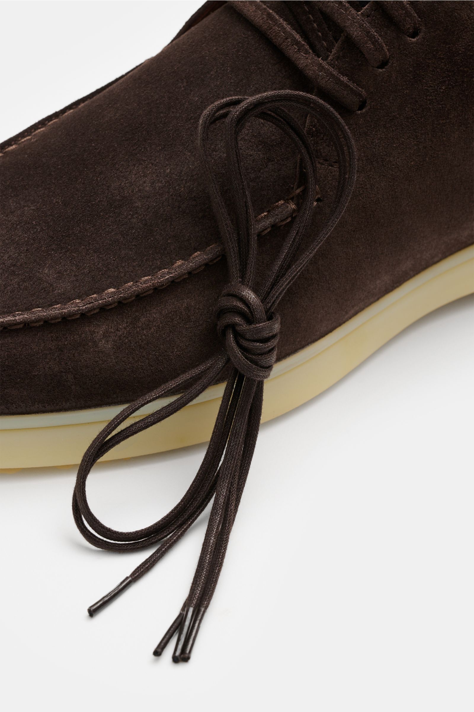 Close-up side view of the Aurélien Desert Boot dunkelbraun in soft dark brown suede with a flexible cream rubber sole and a tied pair of dark brown laces, showing detailed stitching and smooth texture. Stilvoller Allrounder: Die Desert Boots von AURÉLIEN 