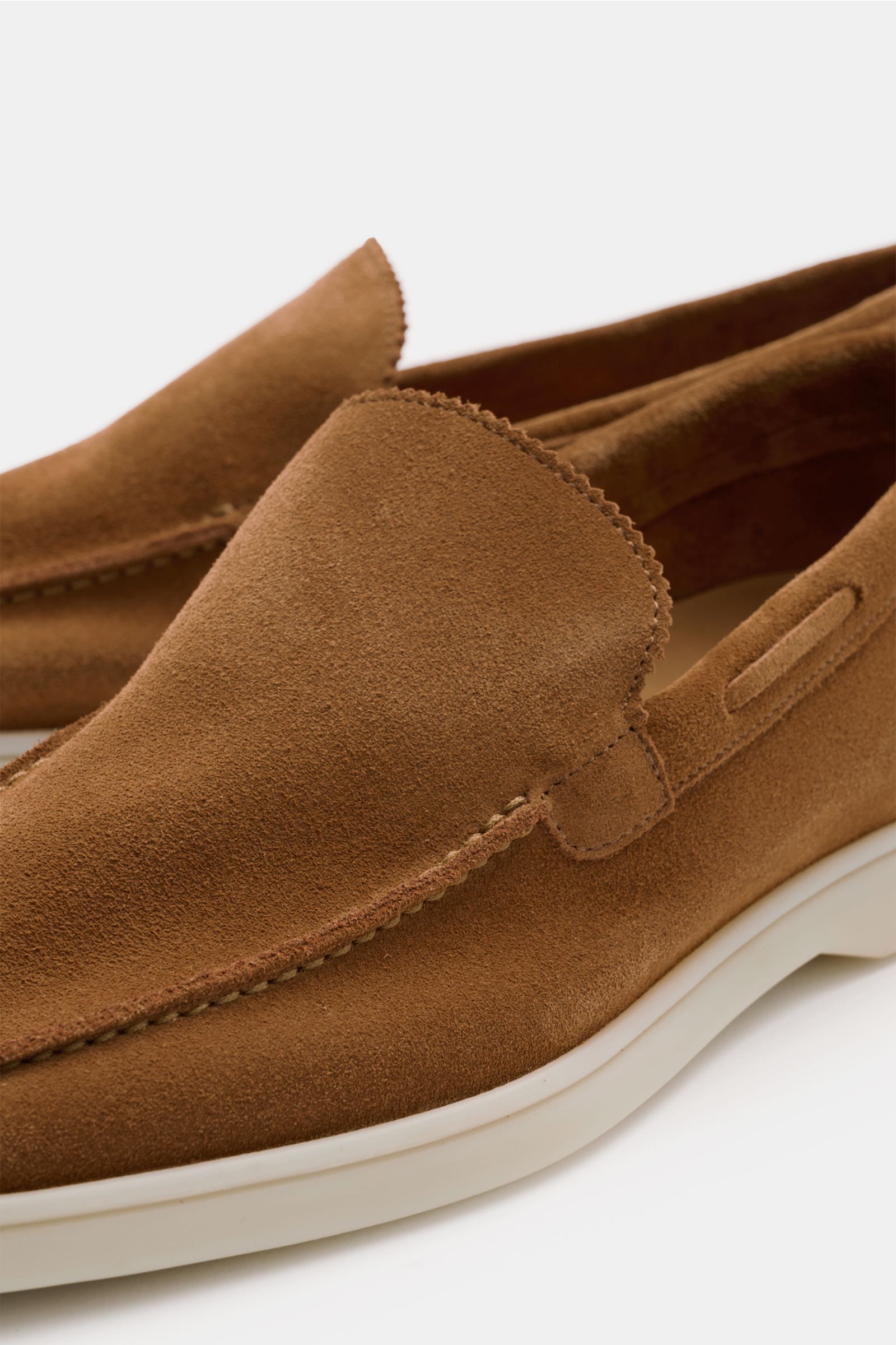 Close-up, angled front-side view of the Aurélien Loafer 'Yacht 2.0' hellbraun in smooth light brown velour leather with a narrow silhouette, discreet zigzag edge on the tongue, hand-stitched seams along the toe, leather lining, and flexible white rubber s