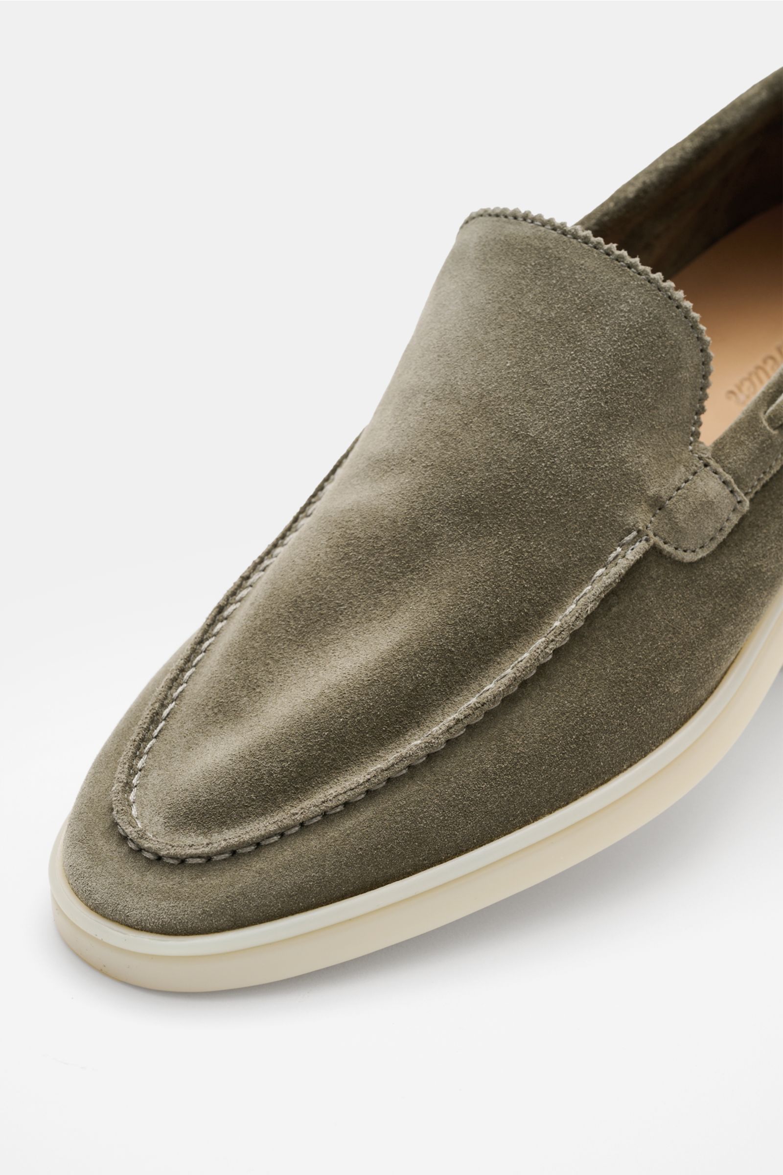 Close-up angled view of the Aurélien Loafer 'Yacht 2.0' oliv in soft olive velour leather, showing hand-stitched seams, zigzag edge on the tongue, and flexible white rubber sole, highlighting its sleek, narrow silhouette and leather lining for breathabili