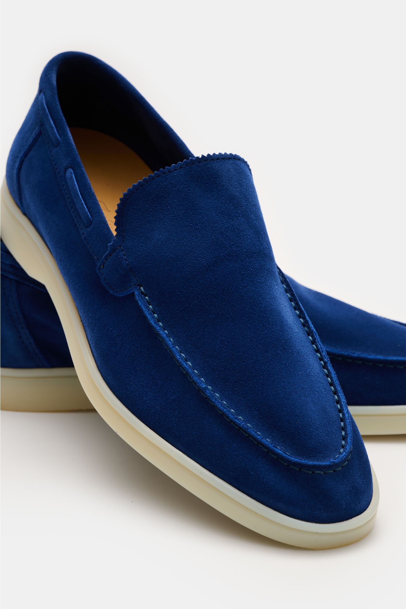 Front-side close-up of Aurélien Loafer 'Yacht 2.0' blau in smooth blue suede with zigzag tongue trim, hand-stitched toe, leather lining, and flexible rubber sole, photographed at an angle showing the top and outer side. Vielseitiger Begleiter: Die Konstru