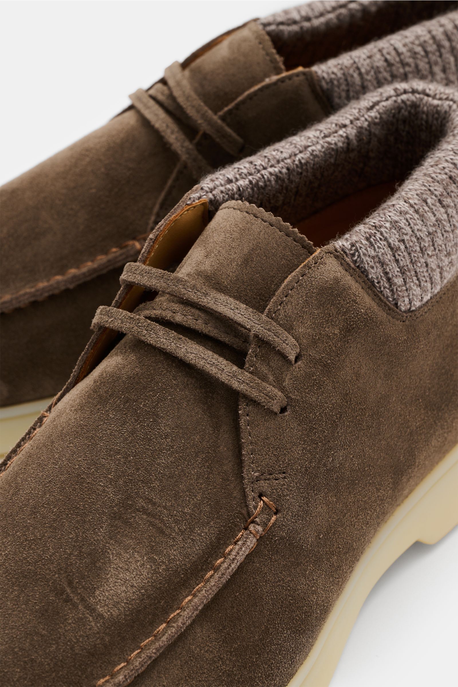 Close-up angled view of Aurélien Desert Boot 'Cashwool' graubraun in soft grey-brown suede with knitted wool collar, open three-eyelet lacing, padded leather interior, distinctive front cap stitching, flexible rubber sole, and an extra pair of laces. Styl