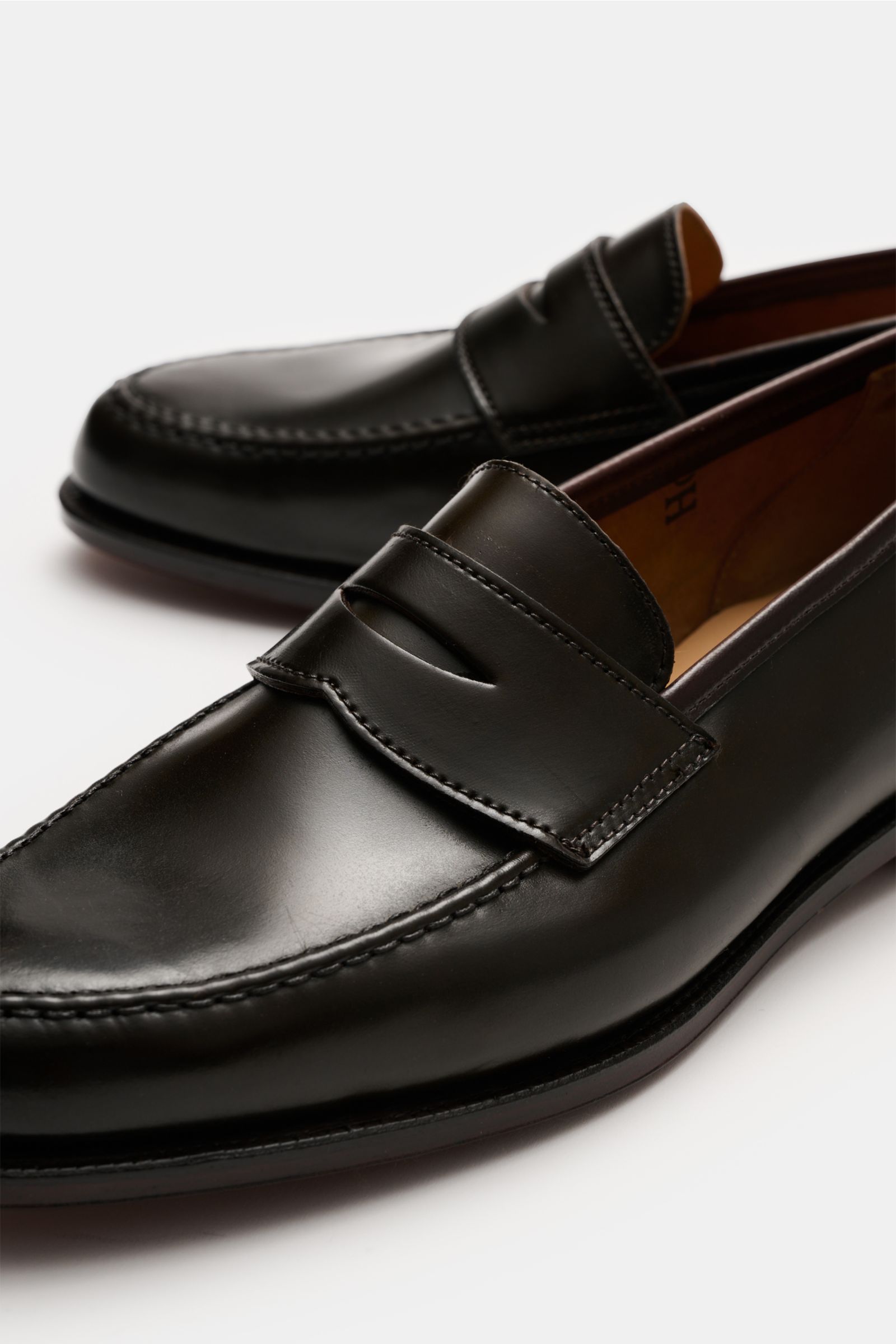 Crockett & Jones Penny Loafer 'Harvard' dunkelbraun aus poliertem Glattleder mit glänzendem Finish und typischem Penny Strap, nah von vorne fotografiert.