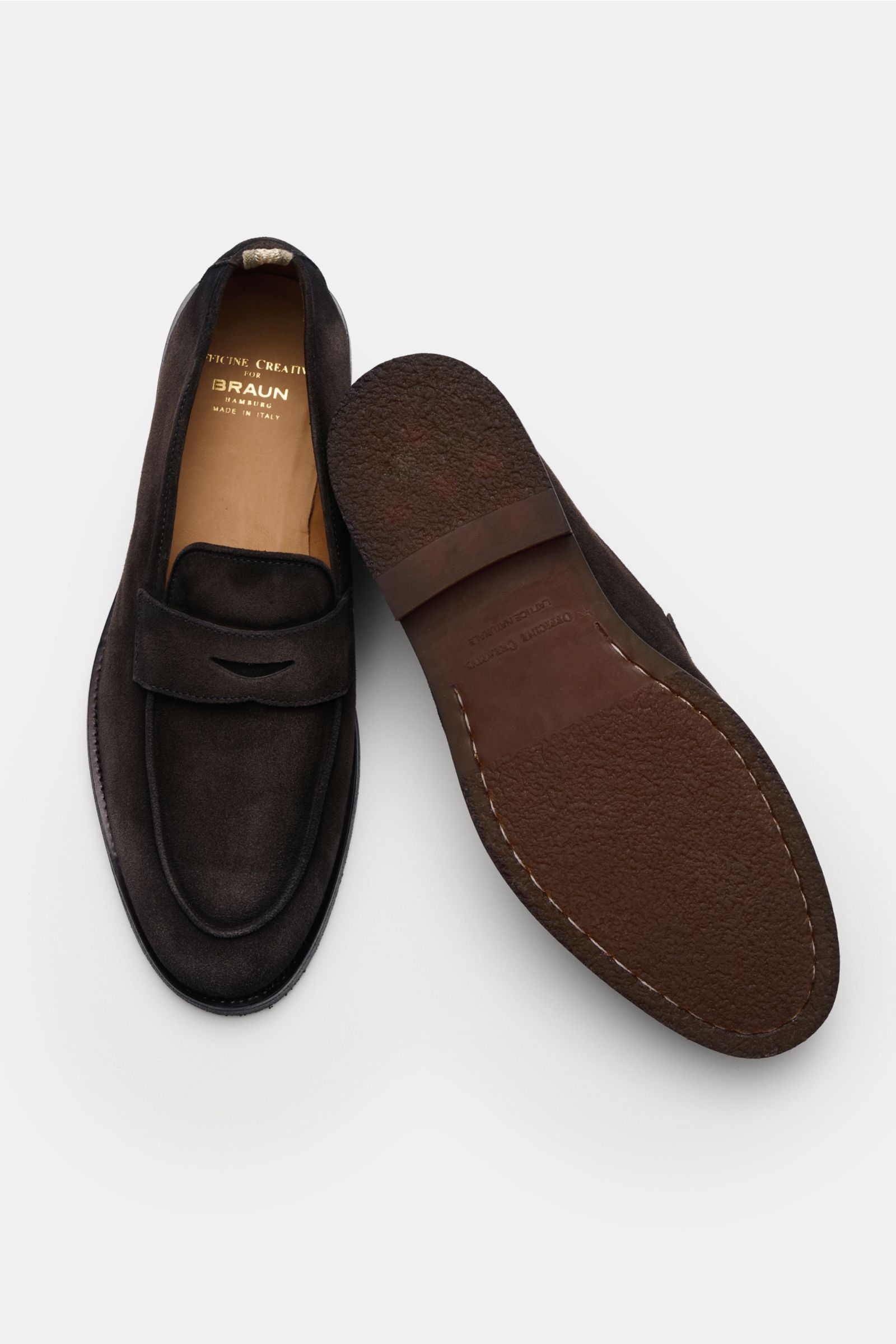 Top view of Officine Creative Penny Loafer 'Opera Flexi 101' dunkelbraun in soft dark brown suede, showing smooth leather interior, natural rubber sole, Goodyear welt, slim silhouette, decorative stitching on front cap, and classic penny strap. Stylish an