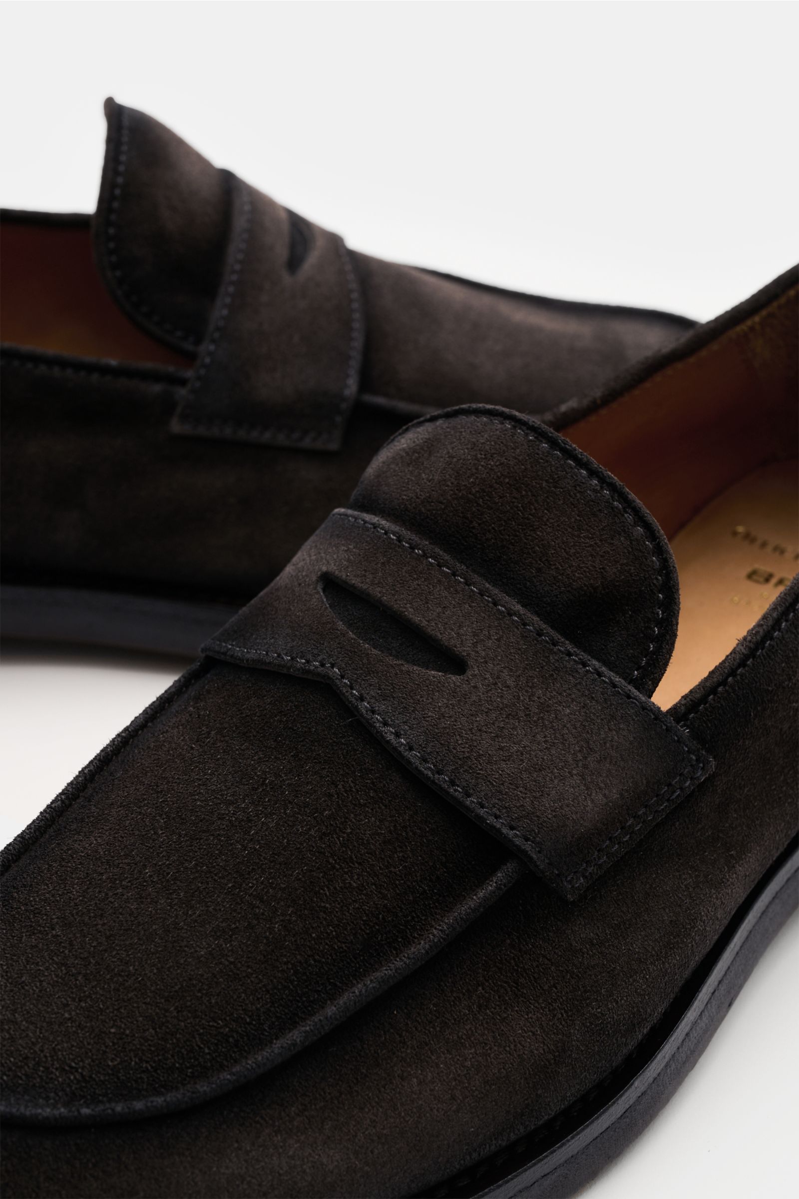 Close-up front-side view of the Officine Creative Penny Loafer 'Opera Flexi 101' dunkelbraun in soft dark brown veloursleder, featuring a sleek silhouette, penny strap, decorative stitching on the toe cap, leather lining, Goodyear welted construction, and
