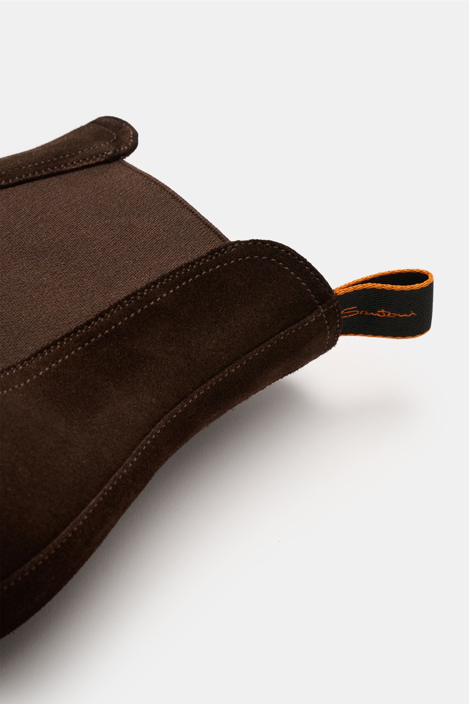 Close-up side view of the Santoni Chelsea Boot 'Adrian' braun, showcasing smooth brown suede, elastic side panel, and orange-trimmed pull tab. Ein Klassiker neu interpretiert: Der Chelsea Boot 'Adrian' von SANTONI vereint geschmeidiges Veloursleder mit ei