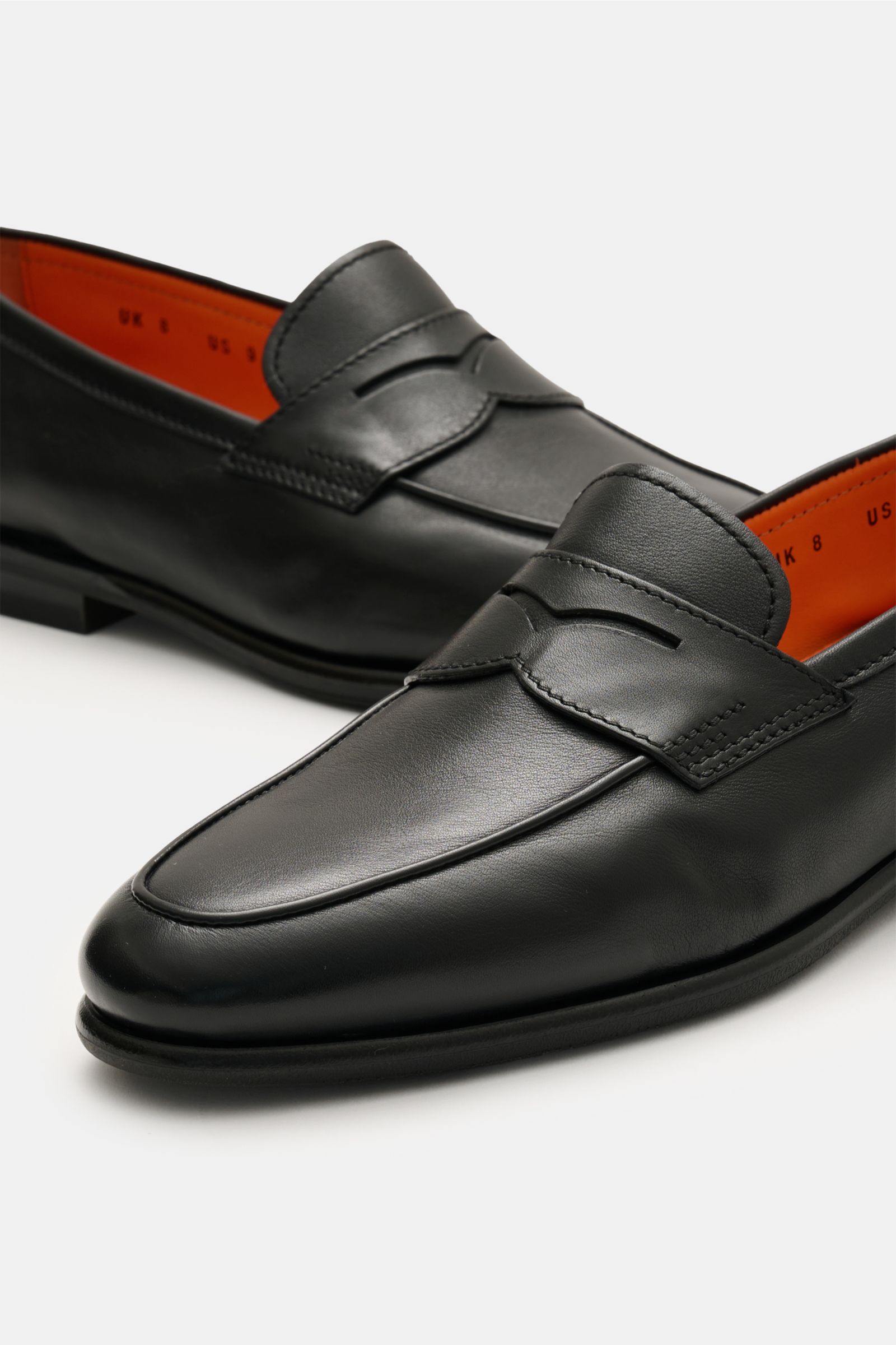 Santoni Loafer 'Carter' schwarz shown from a close-up front-side angle, featuring fine black hand-dyed smooth leather, typical penny-strap, stitched toe cap, leather lining, leather sole with rubber-reinforced heel, Blake construction, and a slim silhouet