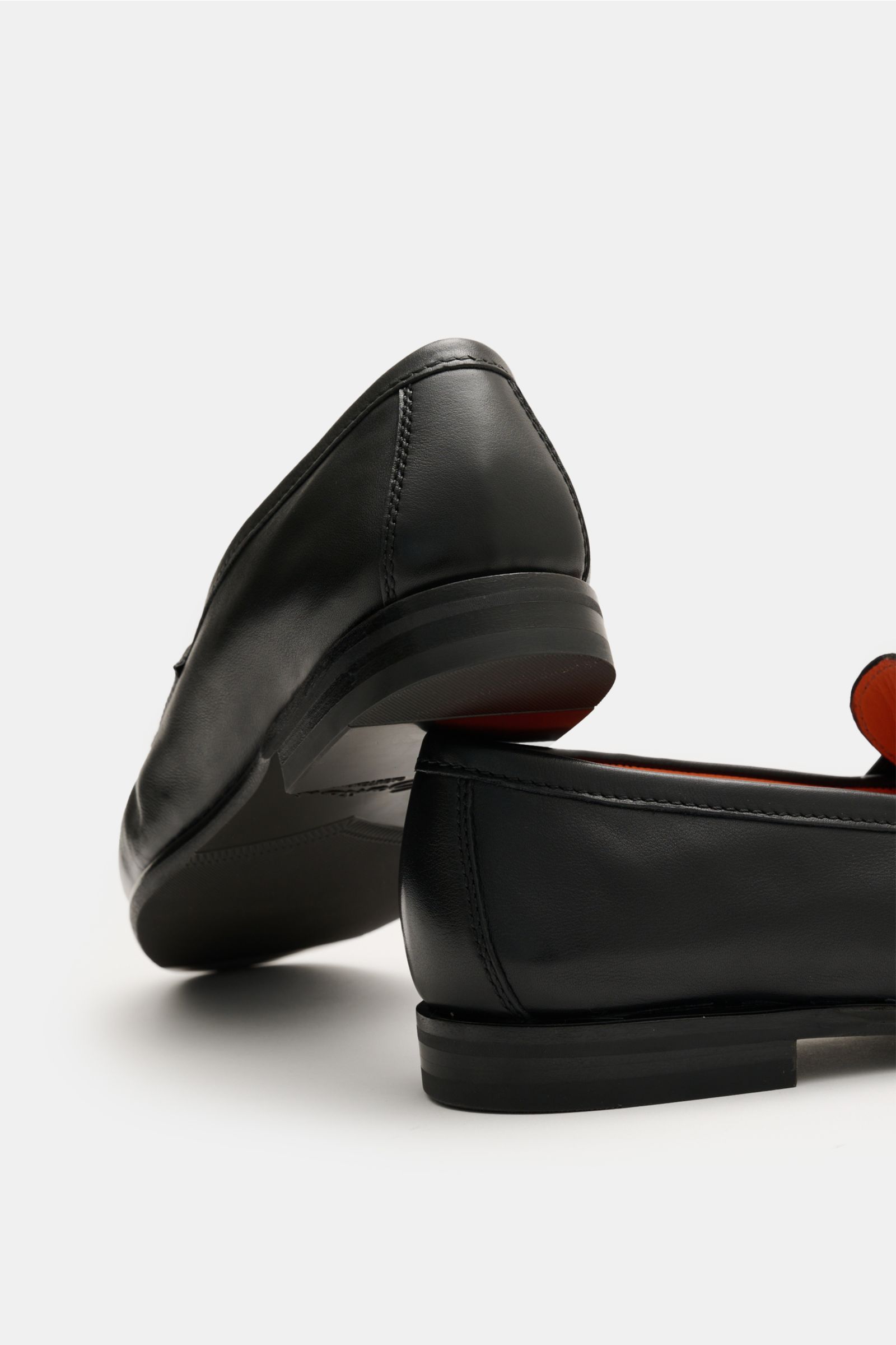 Santoni Loafer 'Carter' schwarz shown from a low rear angle, featuring fine hand-dyed smooth leather, Blake construction, narrow silhouette, penny strap, stitched toe cap, leather lining, leather sole, and rubber-reinforced heel.