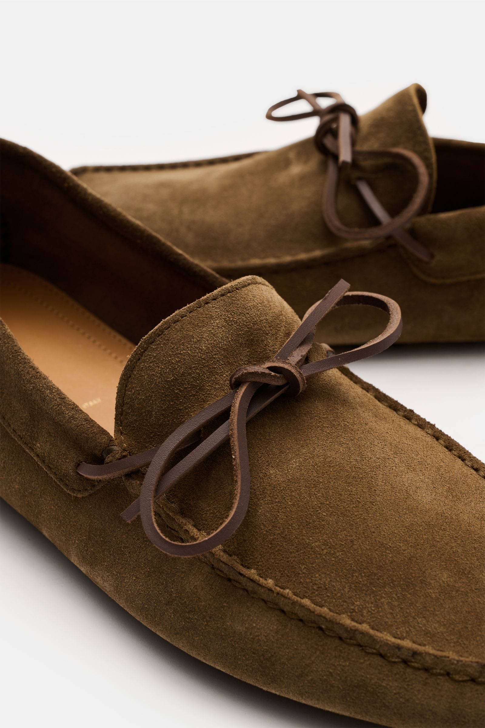 Nahaufnahme von Tom Ford Loafer braun aus softem Veloursleder mit eckig zulaufender Silhouette, Leder-Schleife und Noppensohle, seitliche Perspektive.