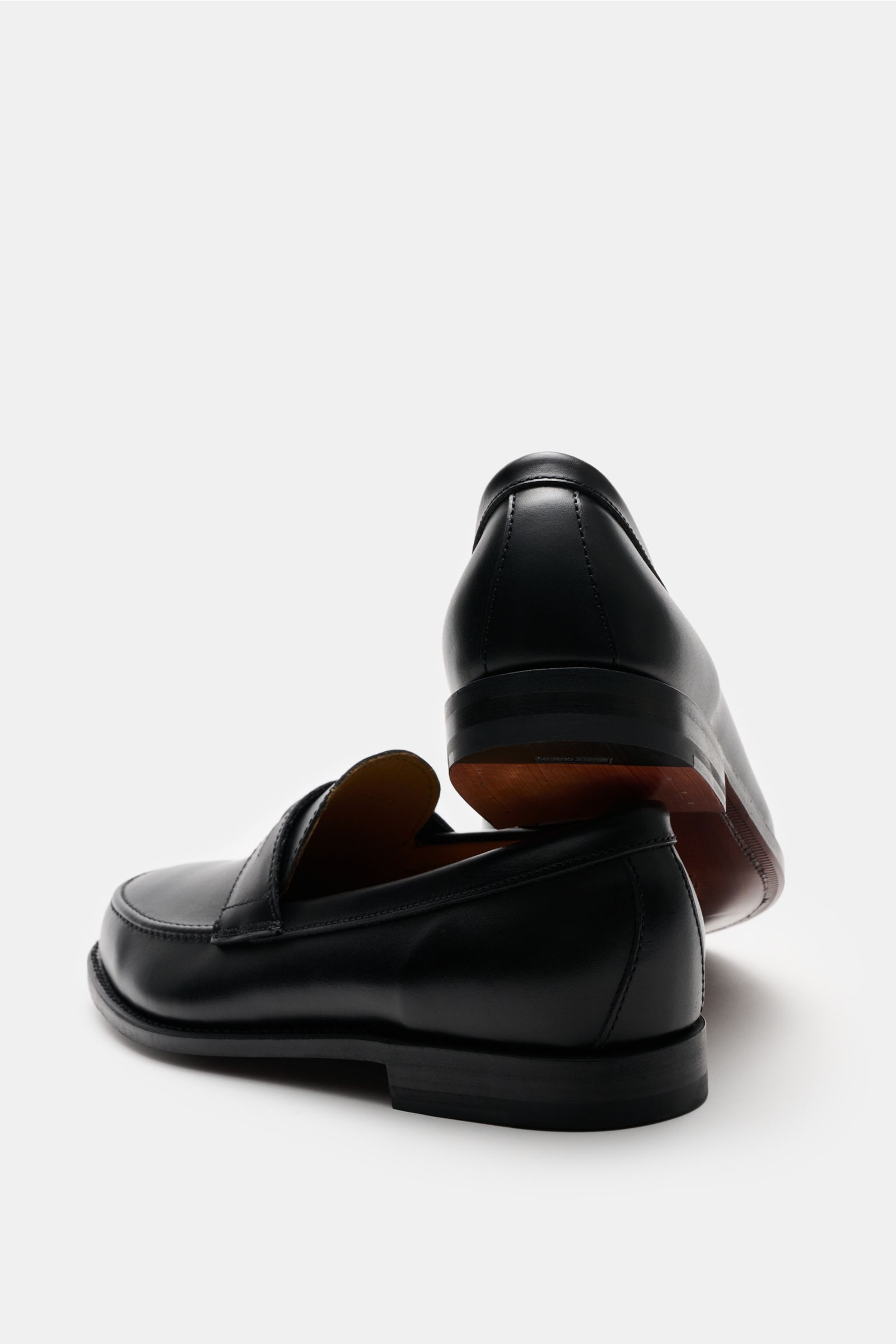 Ludwig Reiter Penny Loafer schwarz, edles Glattleder, schmale Silhouette, Penny Strap, Steppnaht, Lederfutter, Goodyear-welted, lederne Sohle, Absatz, von hinten leicht seitlich fotografiert.