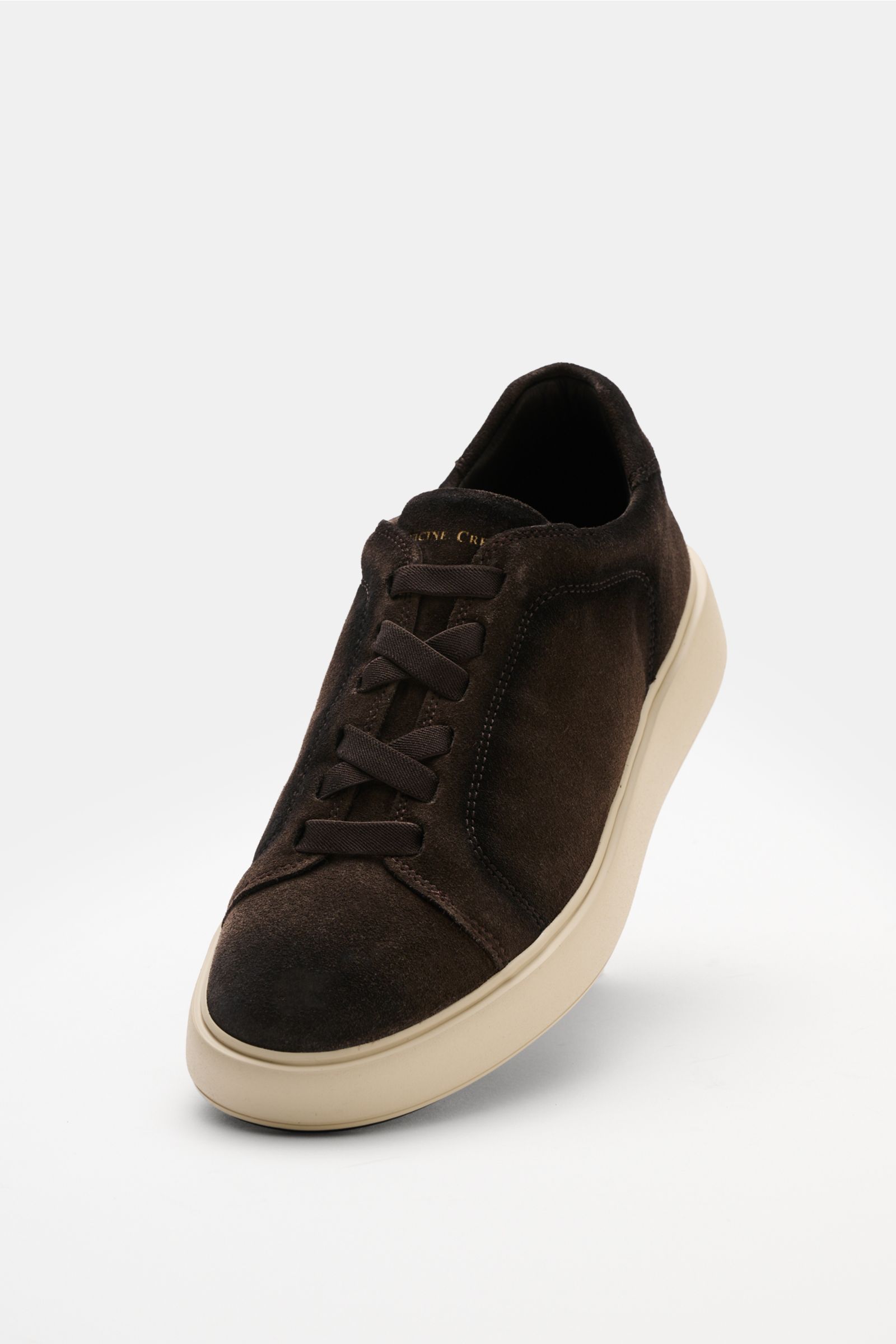 Officine Creative Slip-on-Sneaker 'Slouch 001' taupe shown from a front angle, made of velours leather with round toe, elastic cross bands, gold logo on tongue and heel, padded collar, leather lining, and lightweight rubber sole. When comfort meets timele