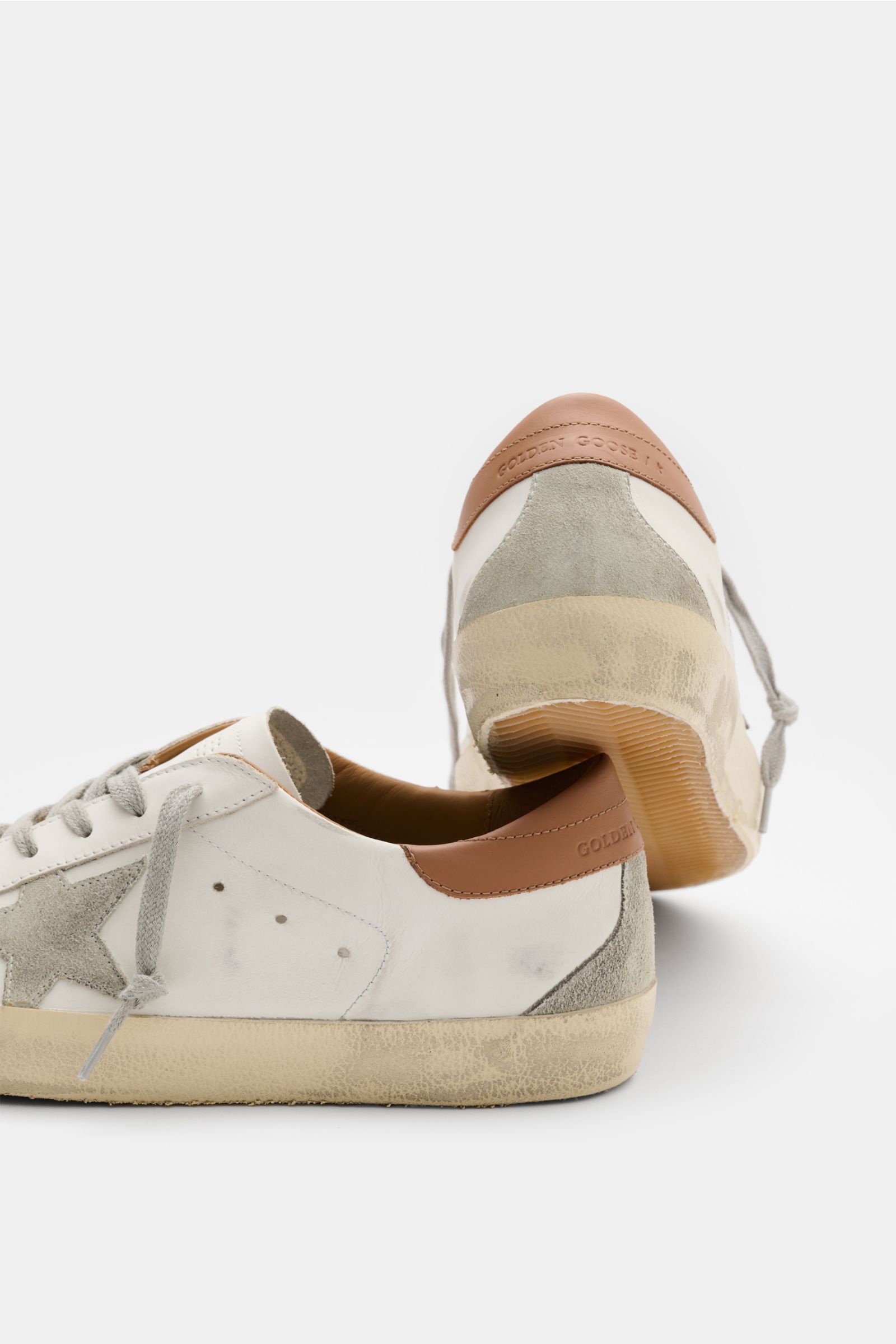 Golden Goose Sneaker 'Super-Star Classic' offwhite/hellbraun shown from rear and side, featuring vintage-finish smooth and suede leather, perforated details, iconic star, seven-hole lacing, padded collar, leather and terry lining, and worn rubber sole. It