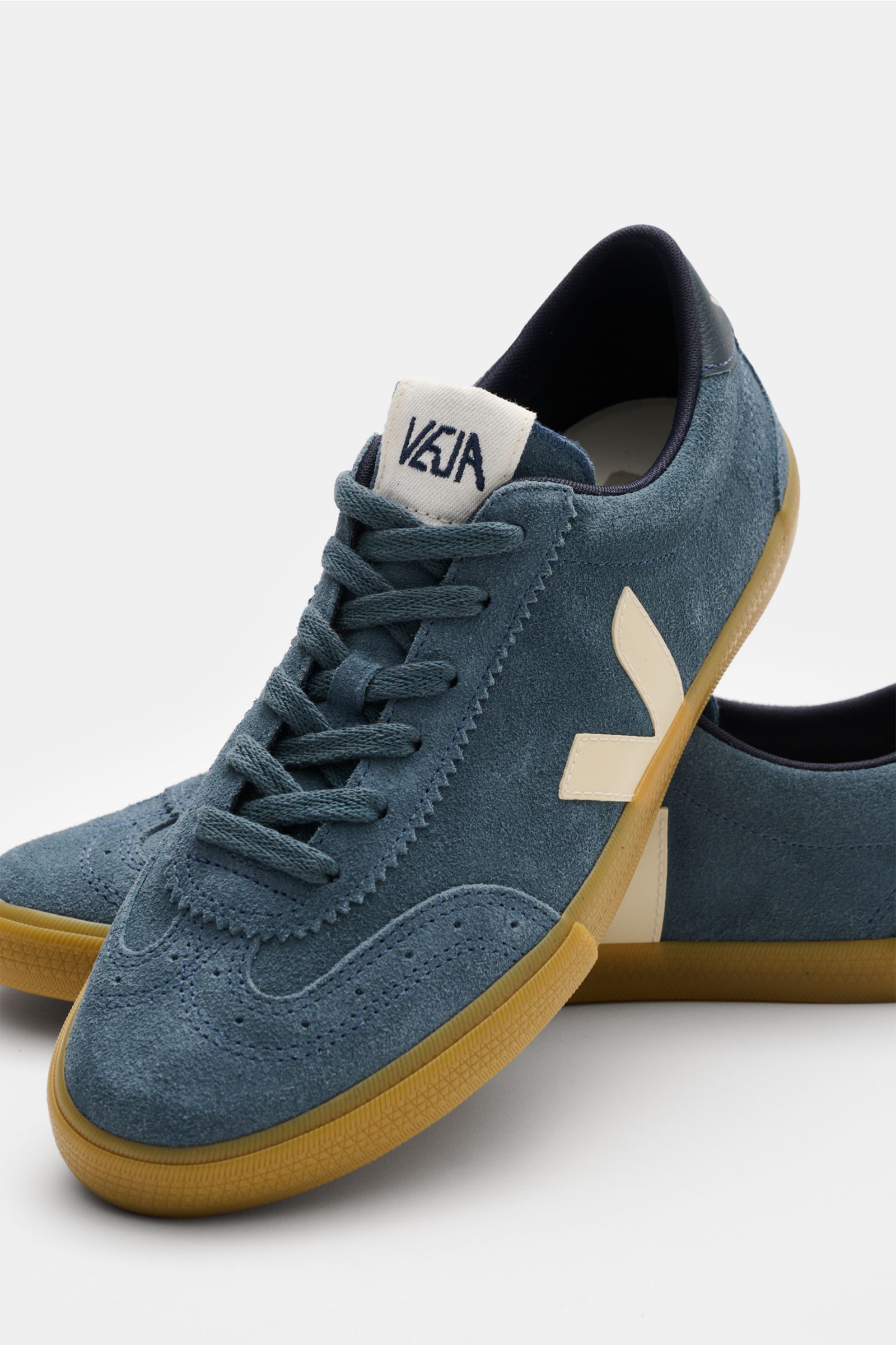 Front-side view of Veja Sneaker 'Volley O.T. Leather' weiß/rot/beige in blue suede with cream V-overlay and gum sole, inspired by 1970s Brazilian volleyball shoes, made from organic traced leather with broguing, six-hole lacing, padded collar, textile lin