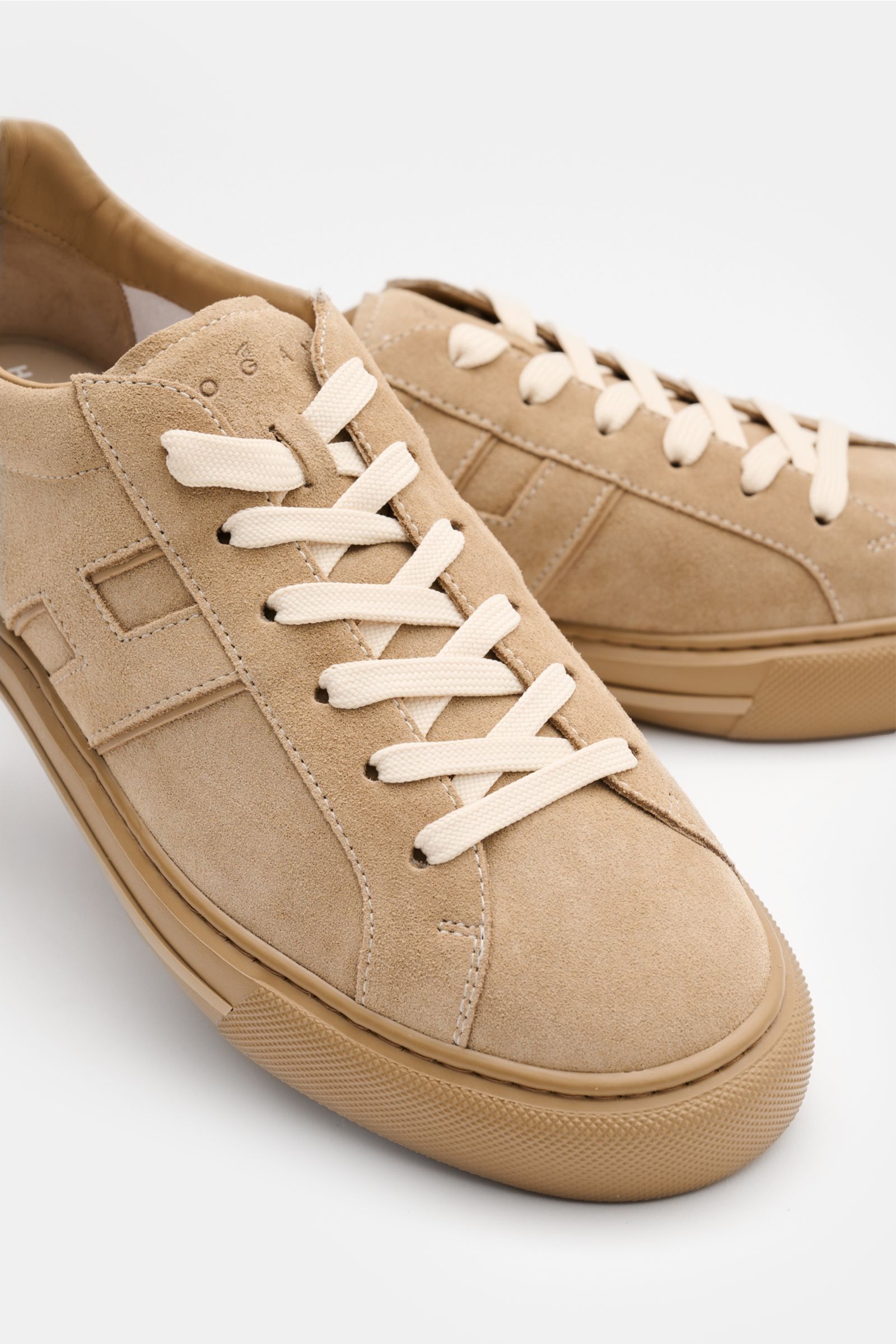 Hogan Sneaker 'Allacciato' beige aus softem Veloursleder, Sechs-Loch-Schnürung, Logo-Print auf Schuhlasche, hoher Schaftrand, H-Form Markeninitial, Leder-Textil Innenfutter, Memory Foam Fußbett, flexible Gummisohle, Nahaufnahme schräg von vorne.