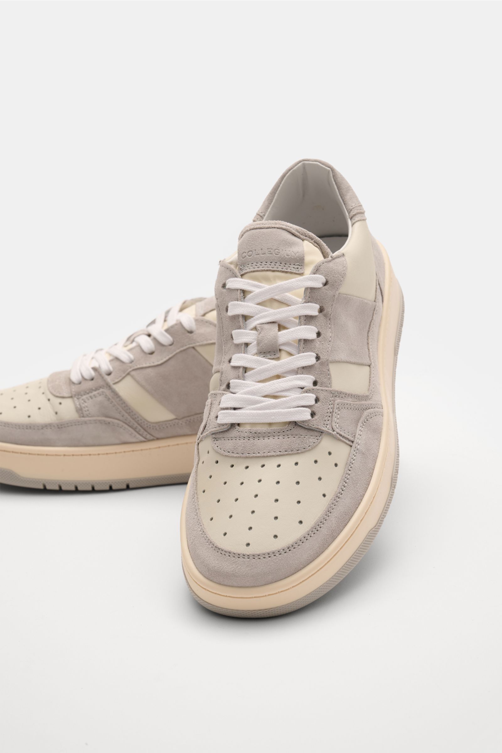 Collegium Sneaker 'Pillar Alpha' offwhite/grau, frontal aus schräger Perspektive, fein genarbtes Glattleder, Velours- und Nubuk-Overlays, sieben-Loch-Schnürung, gepolsterter Schaftrand, Leder-Innenfutter, flexible Gummisohle.