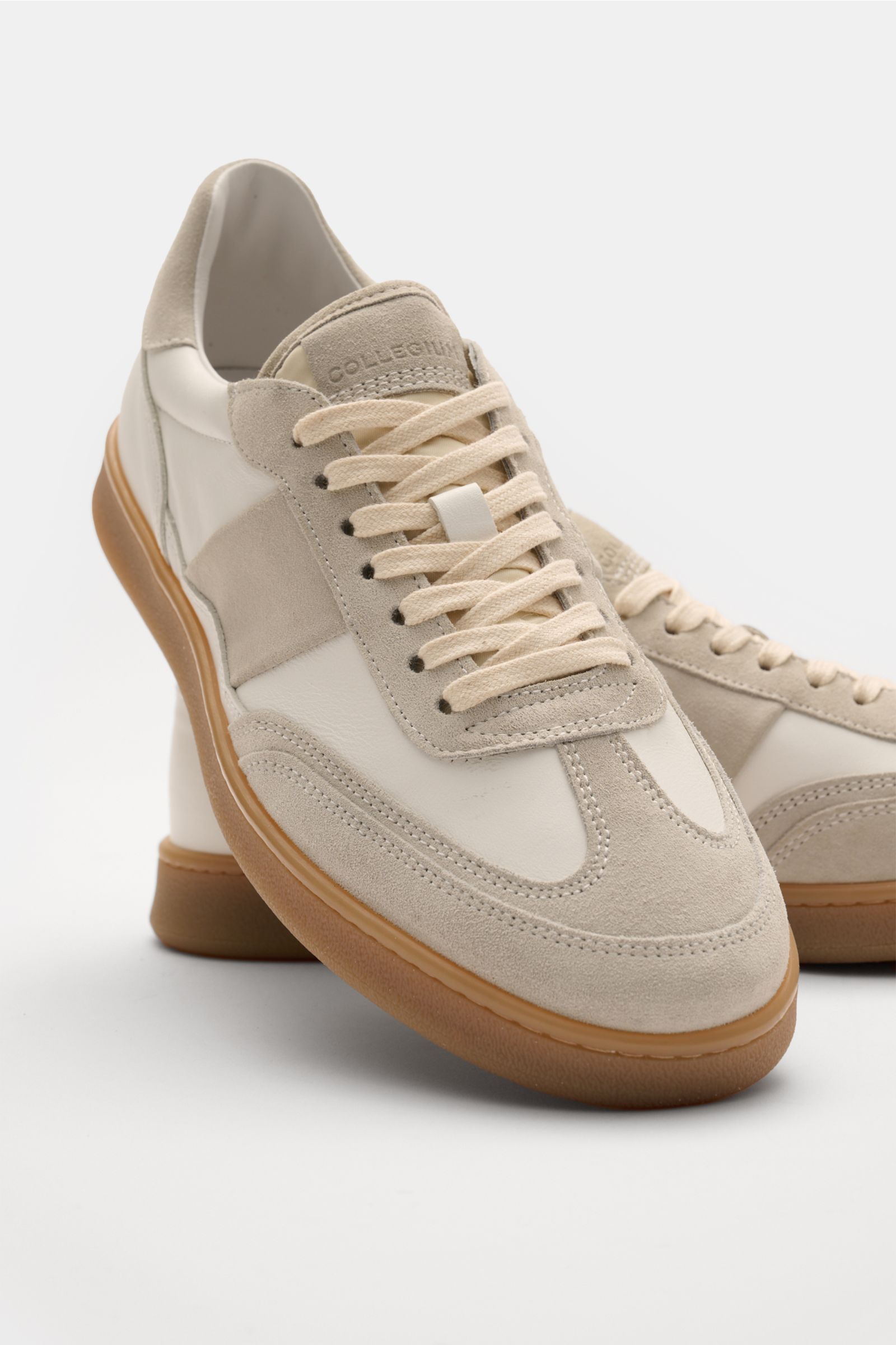 Collegium Sneaker 'Pillar Court II' weiß/hellgrau, frontal schräg fotografiert, fein genarbtes Glattleder, Velours- und Nubuk-Overlays, sieben-Loch-Schnürung, gepolsterter Schaftrand, flexible Gummisohle.