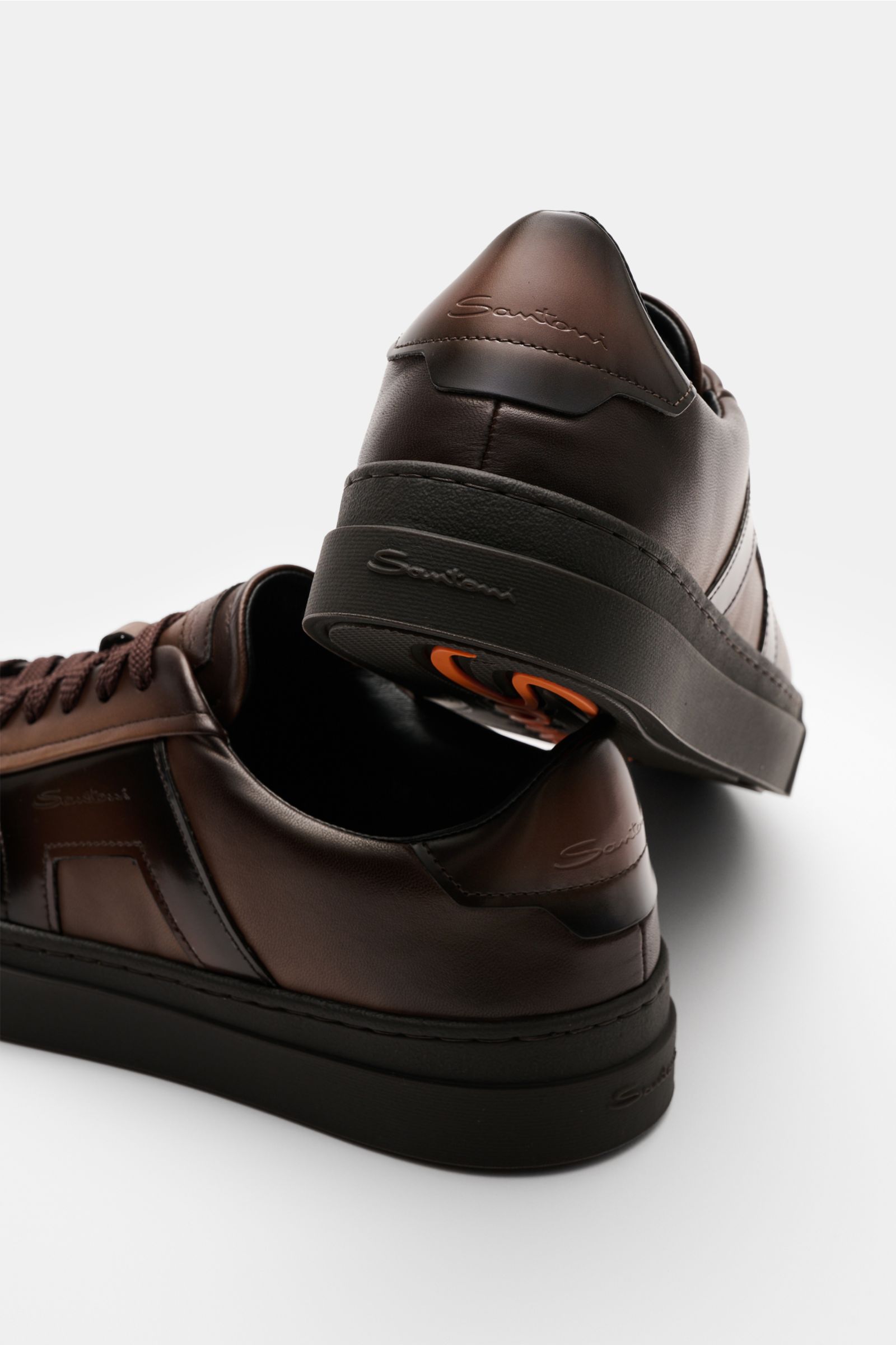 Santoni Sneaker 'Double Buckle' dunkelbraun aus edlem Glattleder, sieben-Loch-Schnürung, runde Vorderkappe, Overlays mit Farbverlauf, goldfarbiges Emblem, gepolsterter Schaftrand, Innenfutter aus Leder, flexible Kautschuksohle mit Schriftzug, Rückansicht.
