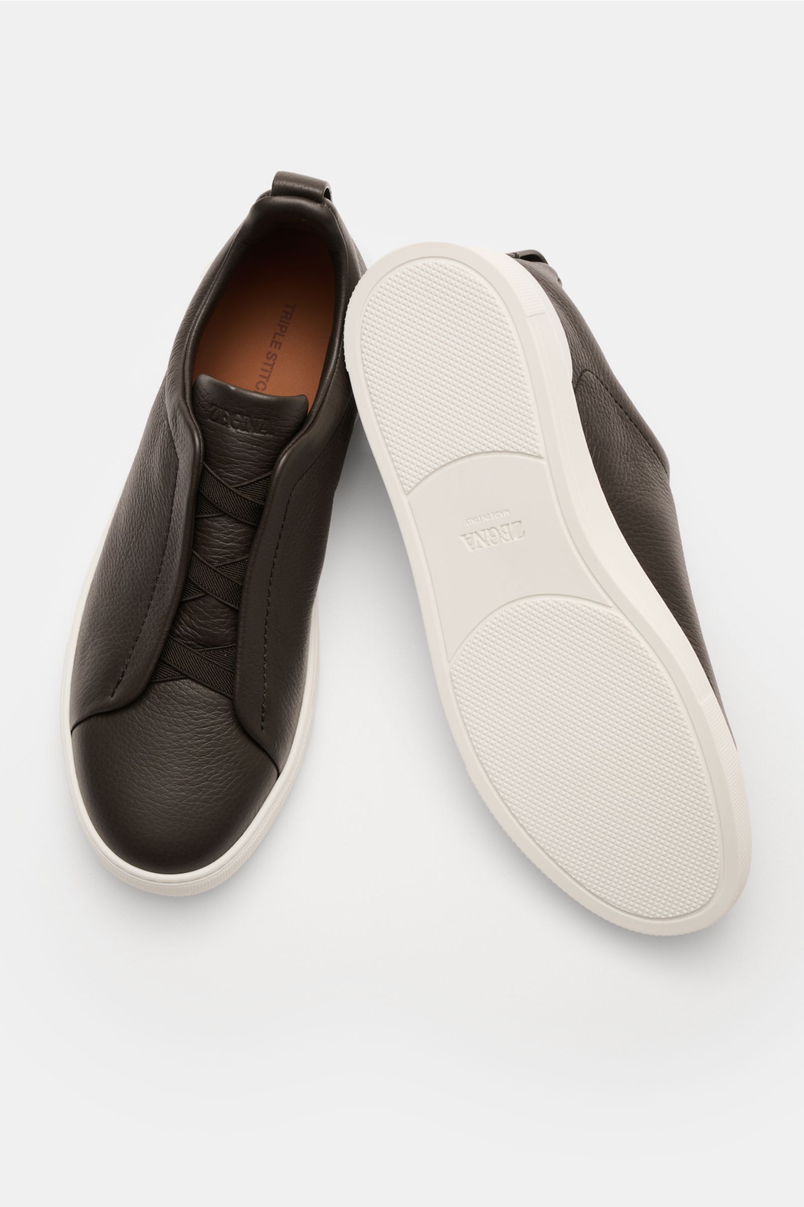 Top-down view of Zegna Slip-on-Sneaker 'Triple Stitch' navy in grained smooth leather with round toe, elastic cross bands, padded collar, pull tab, ZEGNA embossing, leather lining, and white flexible rubber sole, highlighting comfort and minimalist design