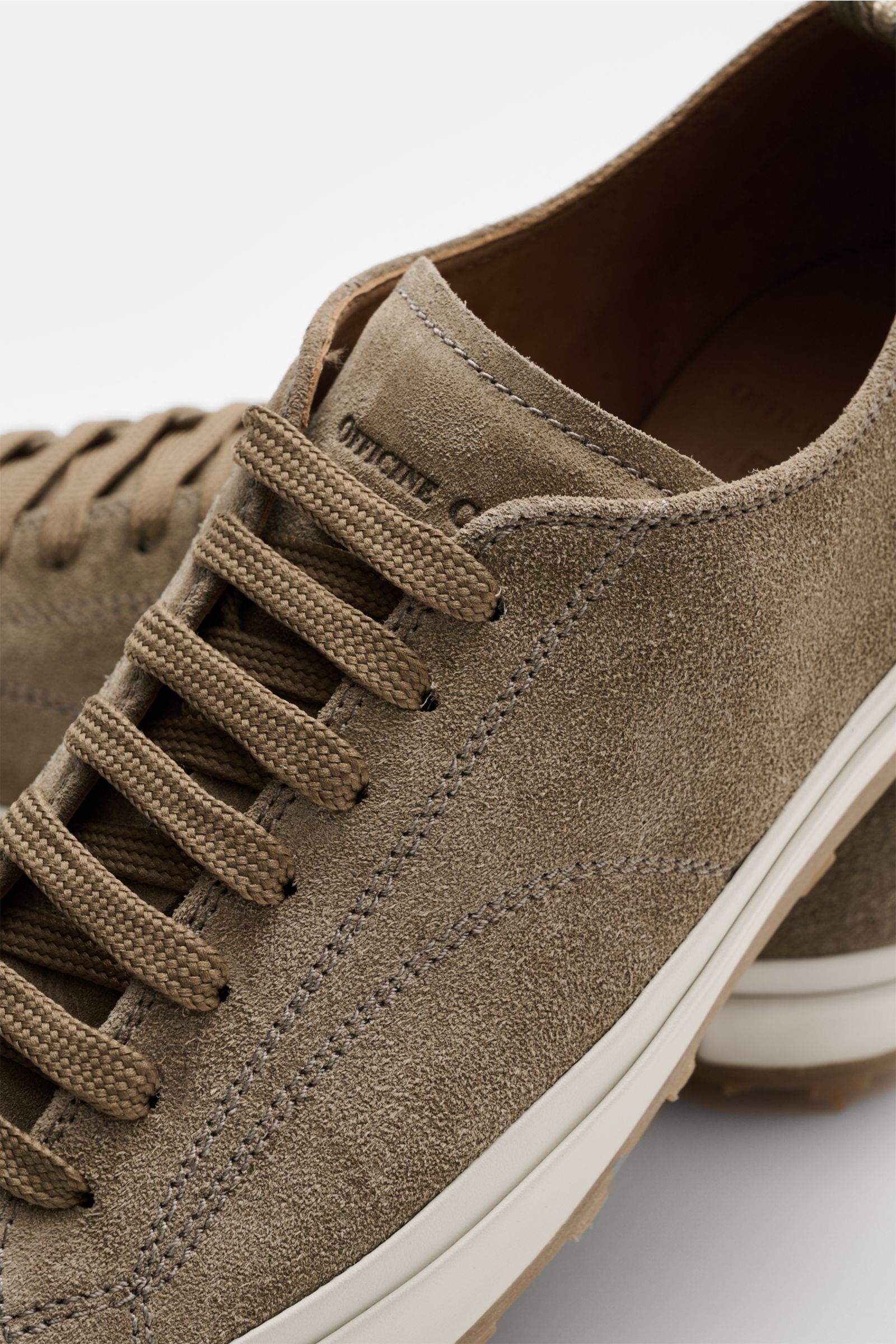 Close-up side and top view of Officine Creative Sneaker 'Vulcan' taupe in noble suede with round toe, seven-eyelet lacing, logo-embossed tongue, leather lining, and textured rubber sole, showcasing a modern retro look for office and leisure outfits.