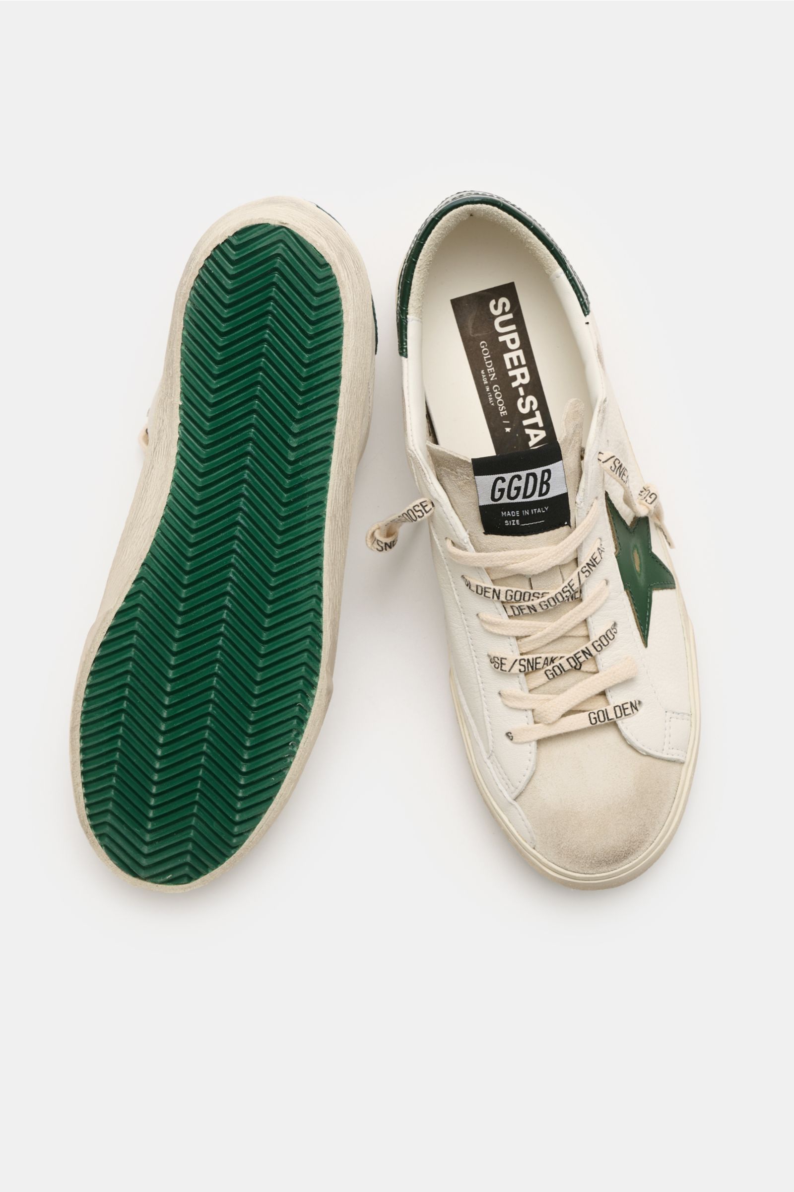 Golden Goose Sneaker 'Super-Star Classic' offwhite/dunkelgrün, vintage-finished, aus feinem Nappaleder, mit grünem Stern, Used-Optik, von oben fotografiert.